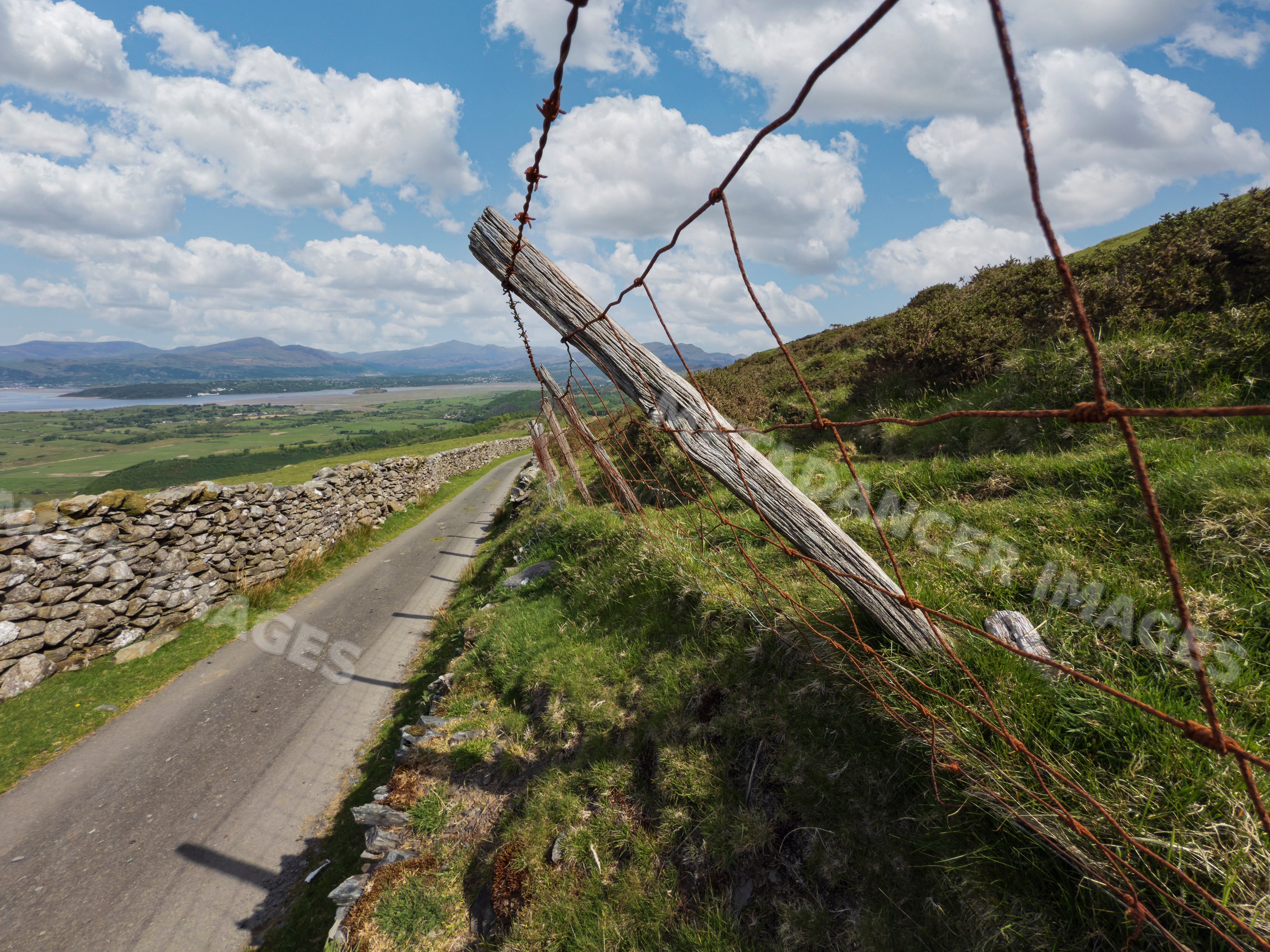 Rural road and wire fence overlooking countryside in harlech, Wales
