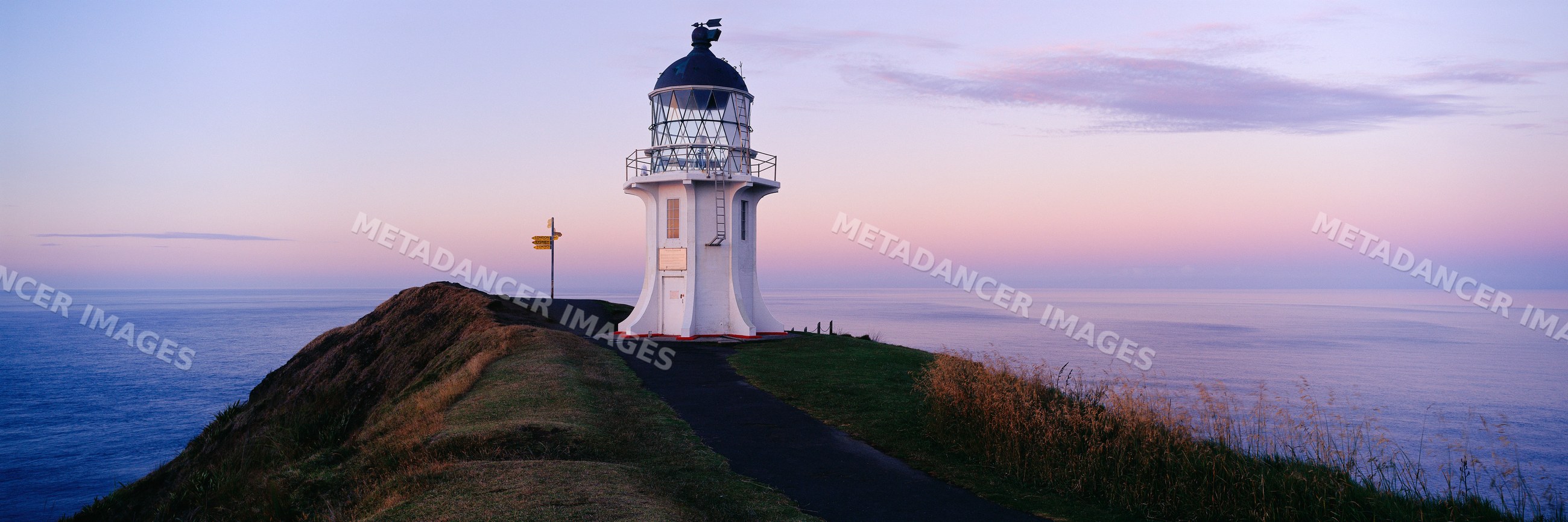 Lighthouse on coastal cliff at sunset with ocean view and twilight sky