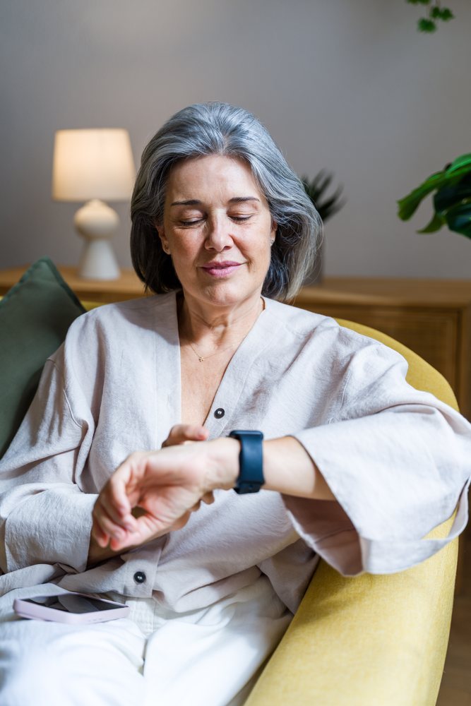 White woman checking smartwatch while seated indoors on yellow chair