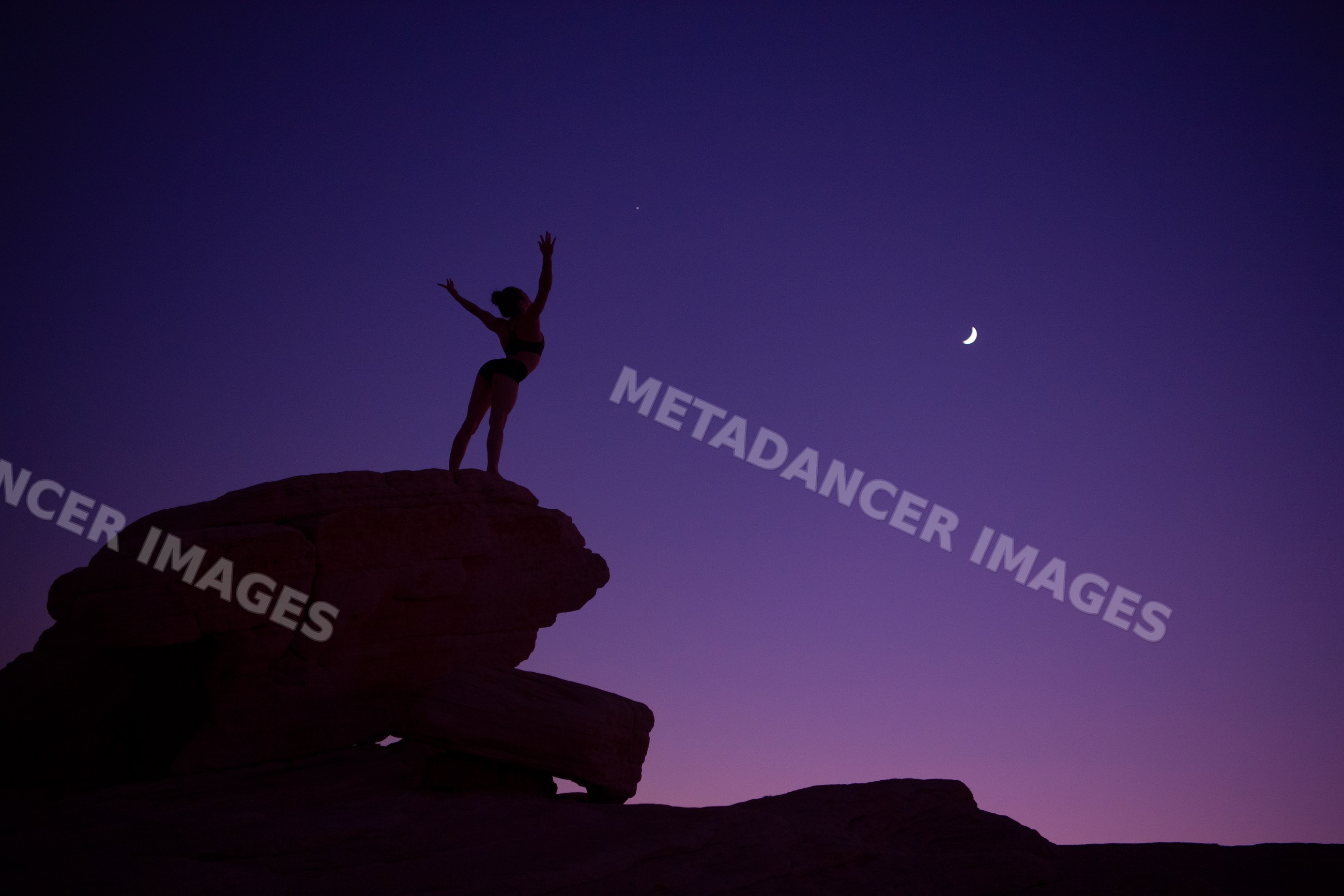 White woman standing on rock practicing yoga