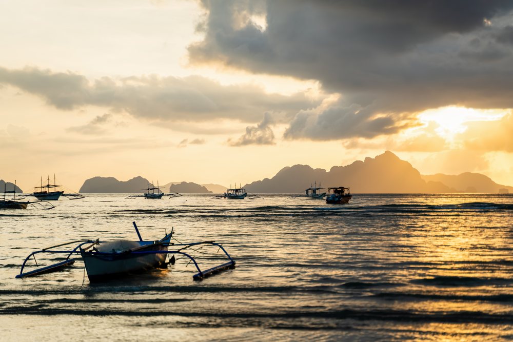 Fishing boats at sunset on the sea with distant islands