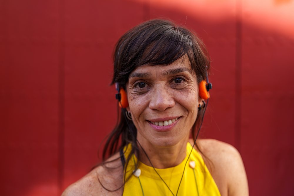 Portrait of smiling Hispanic woman wearing orange headphones outdoors