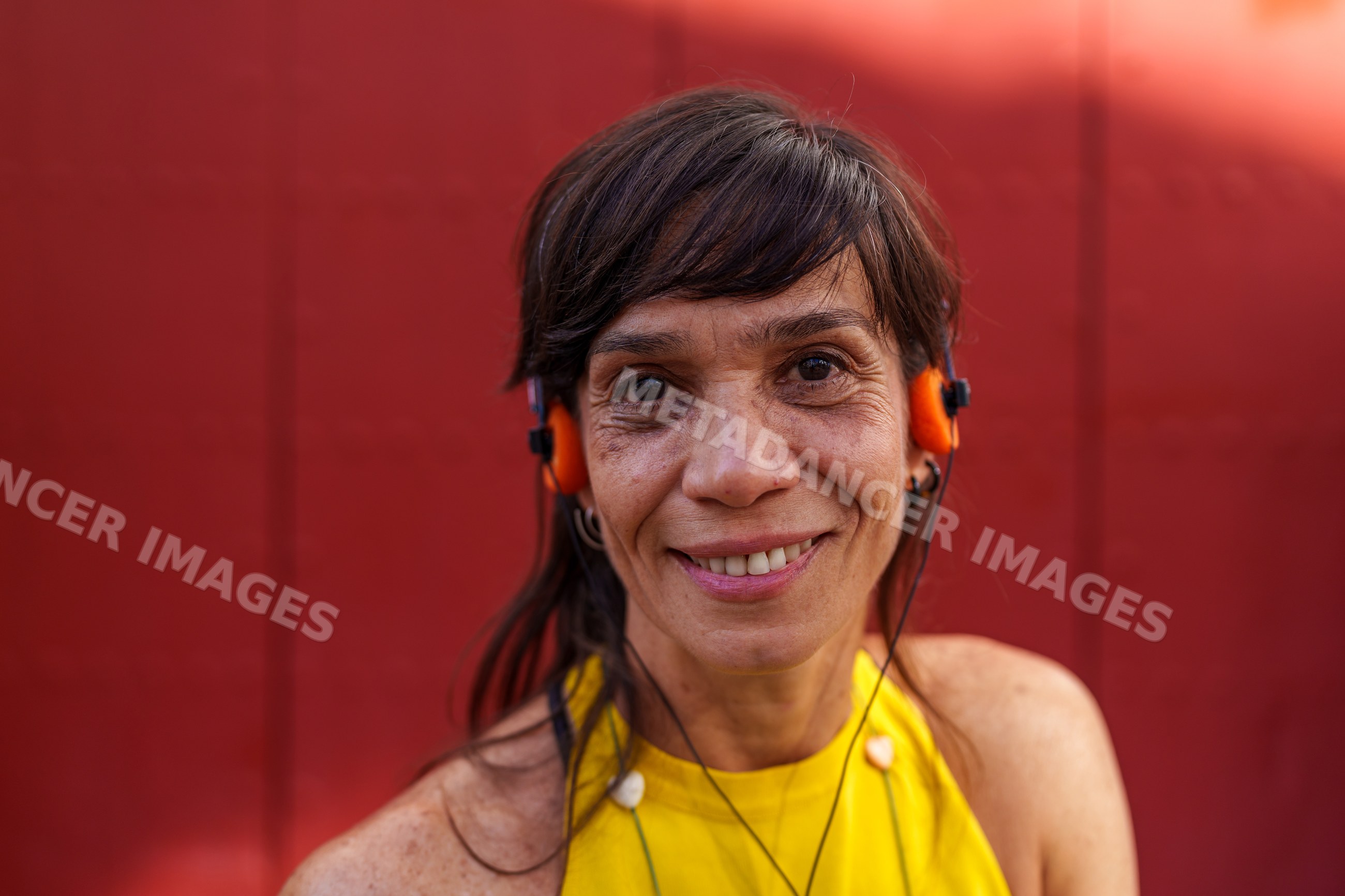 Portrait of smiling Hispanic woman wearing orange headphones outdoors