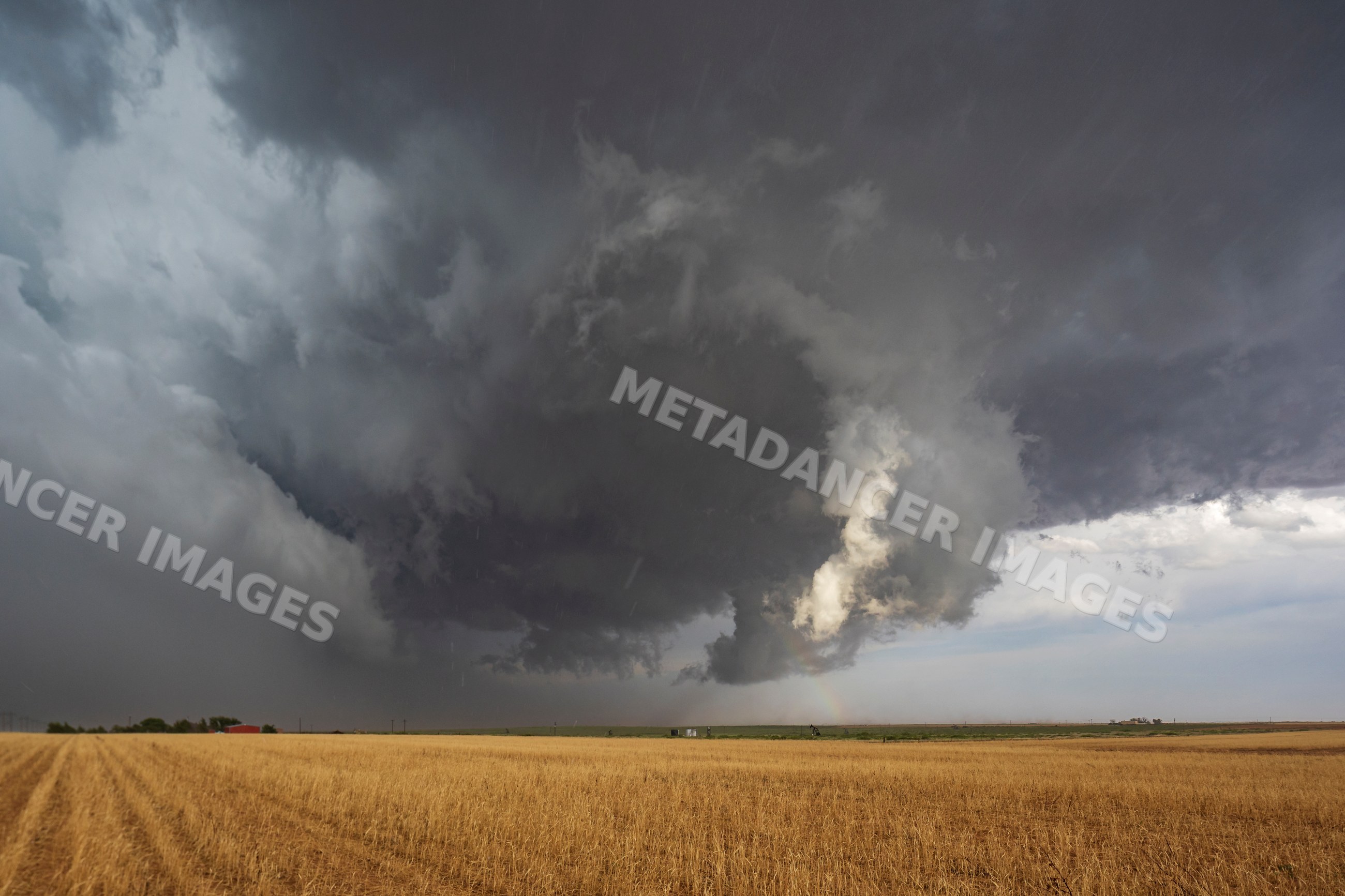 Supercell storm with dark clouds and rainbow over field in levelland