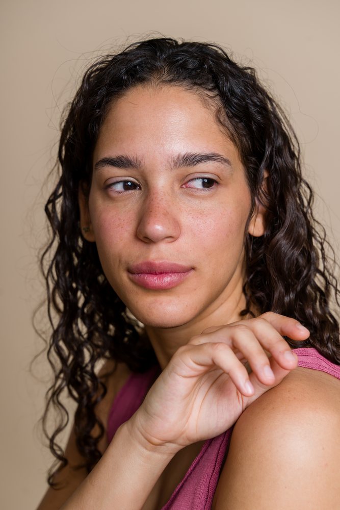 Close-up portrait of a Hispanic woman with curly hair and freckles