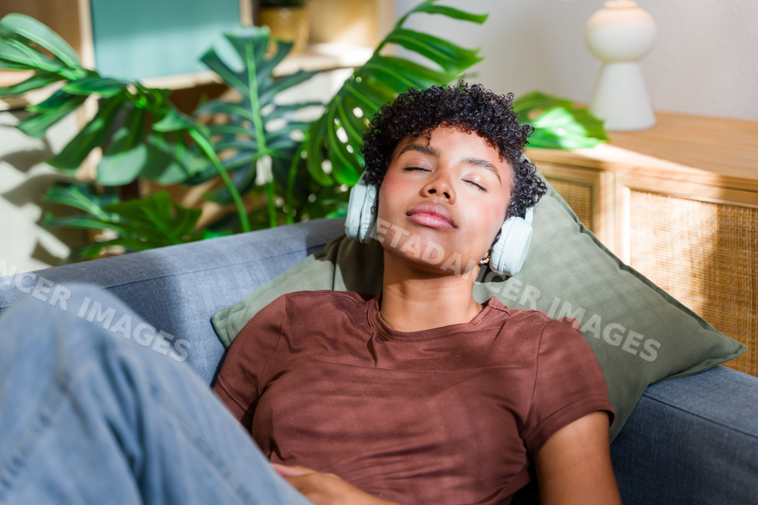 African American woman relaxing with headphones on sofa