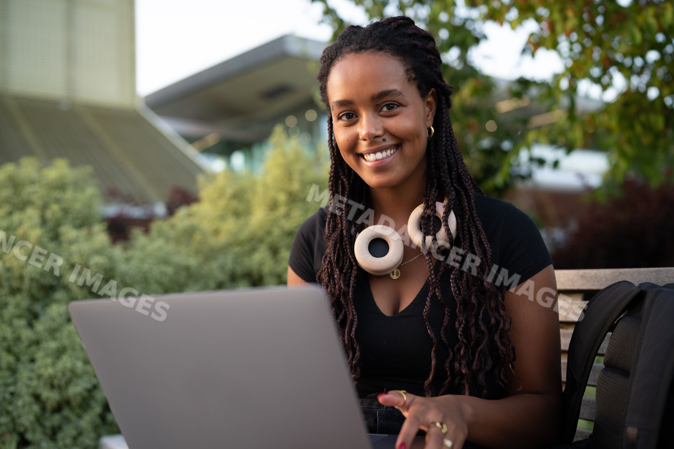 A African American woman works on her laptop outdoors