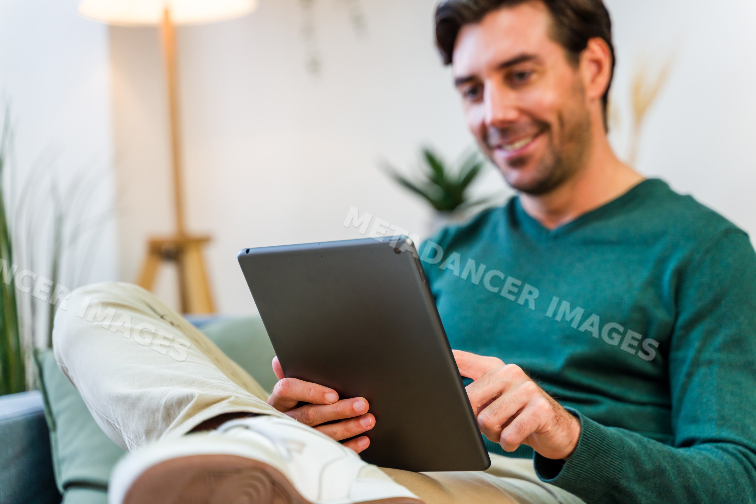 White man using tablet on couch in living room
