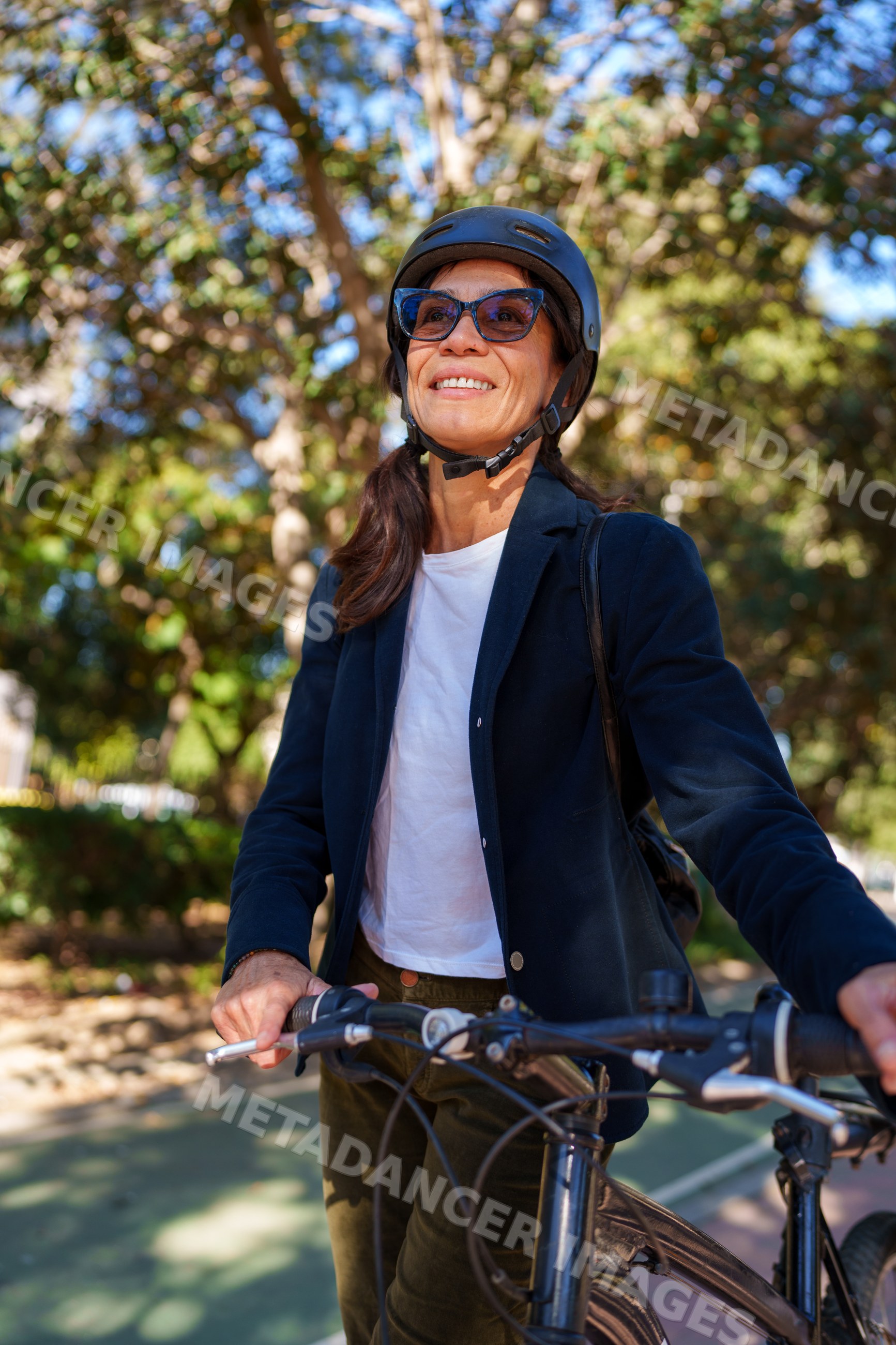 Hispanic woman holding bicycle outdoors in park in Málaga
