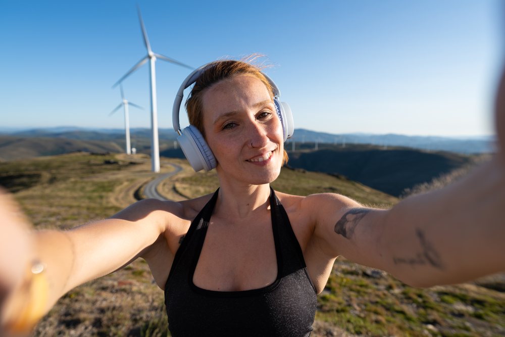 Young white woman taking a selfie at a wind farm in Galicia, Spain