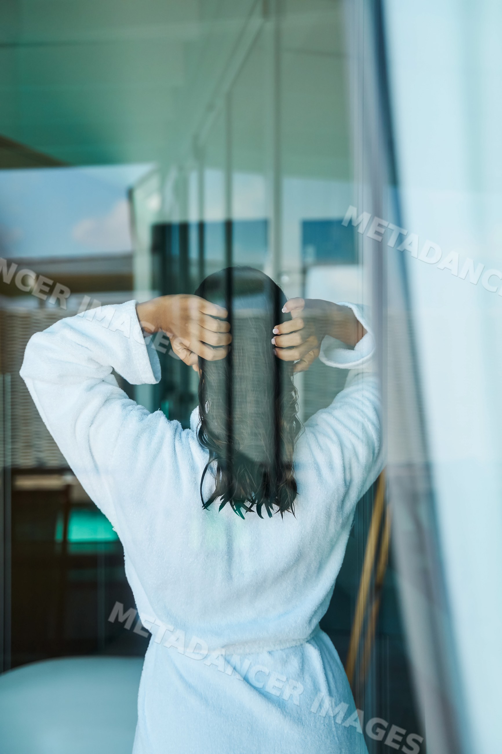 Woman standing with wet hair in white bathrobe indoors
