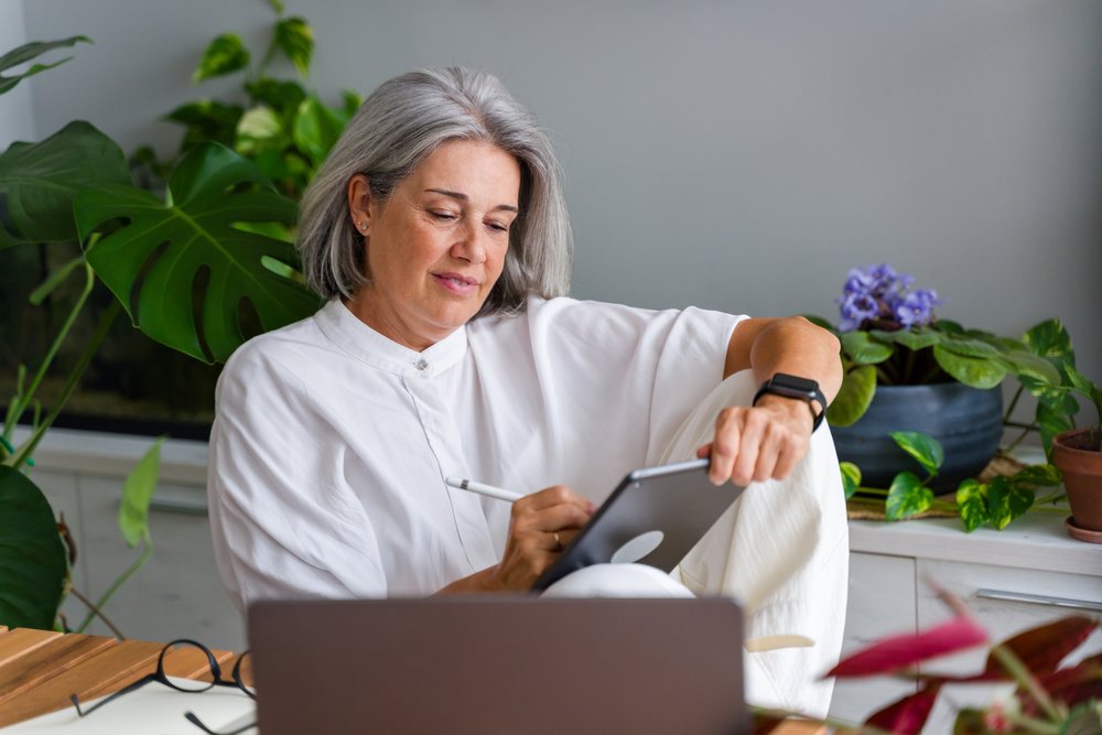 White Woman working with tablet and digital pen in indoor workspace