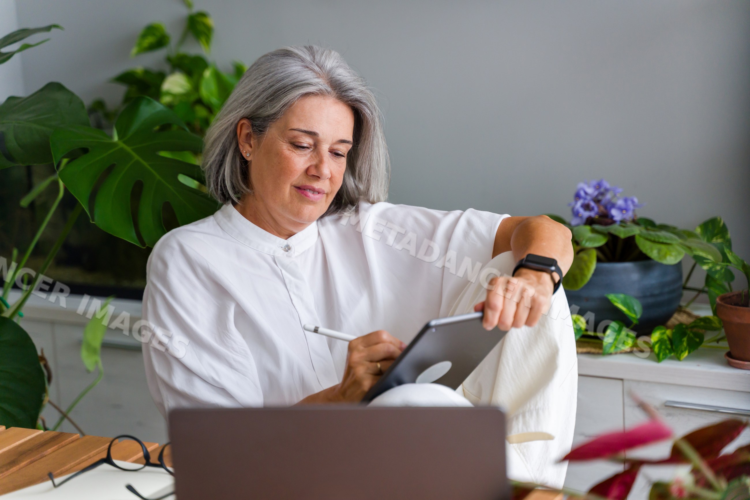 White Woman working with tablet and digital pen in indoor workspace