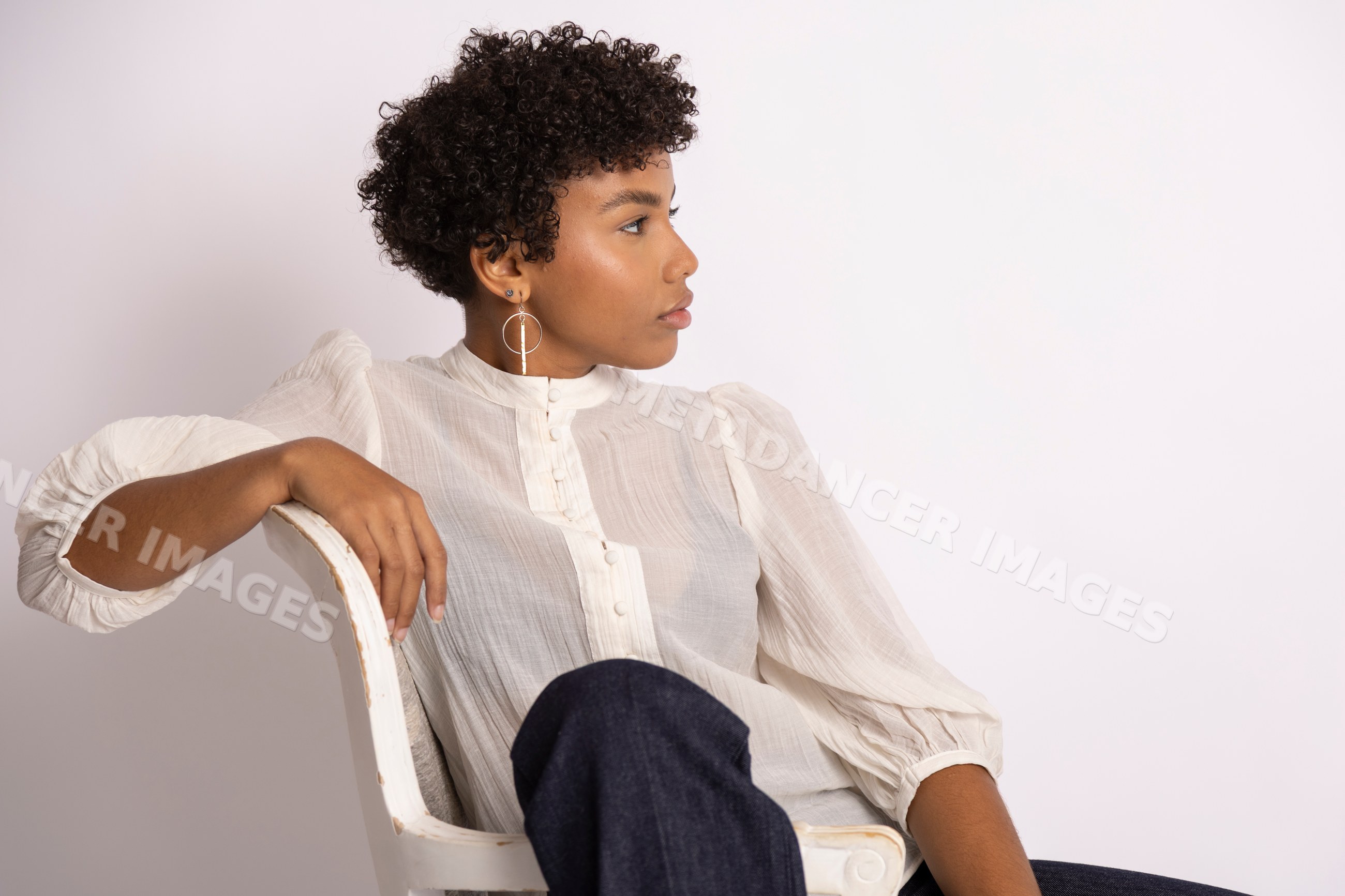 Hispanic woman sitting on chair wearing white blouse and dark pants