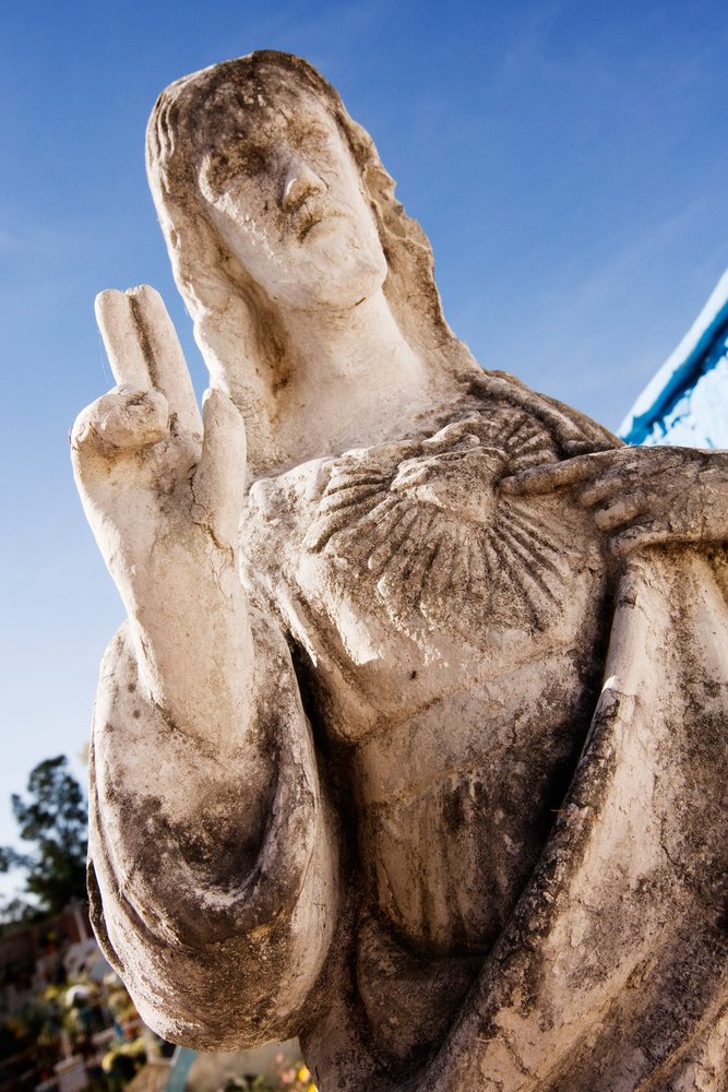 Weathered stone statue of jesus christ making blessing gesture