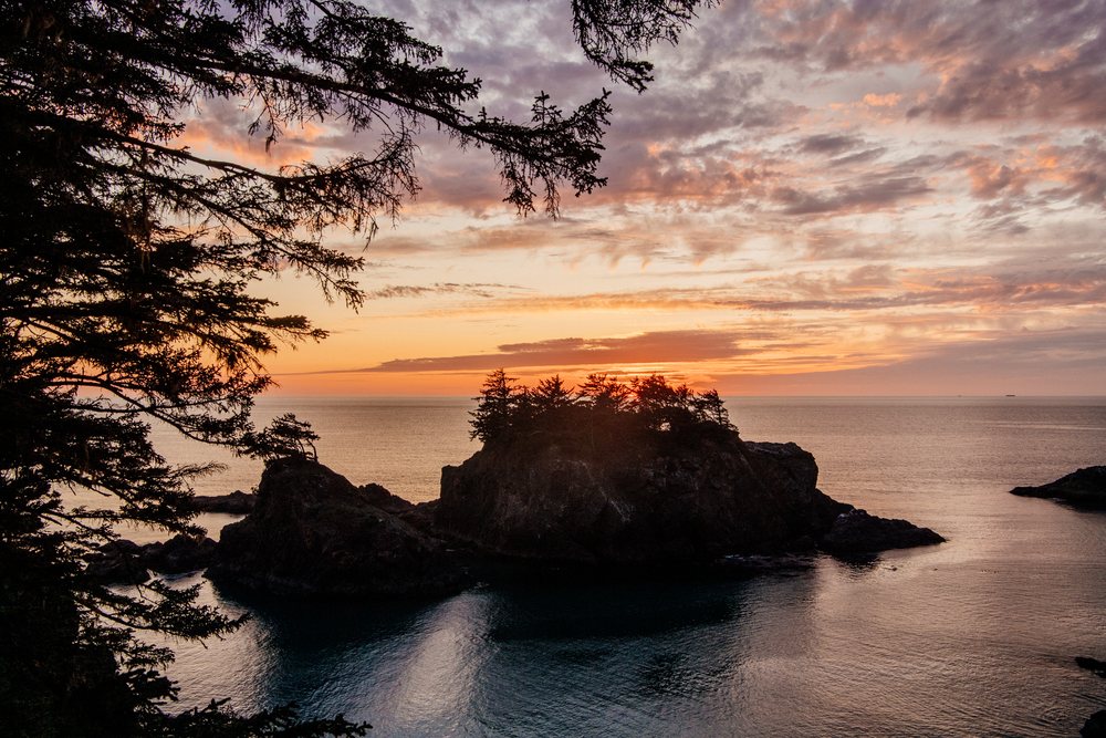 Sunset over rocky island with trees in ocean Oregon