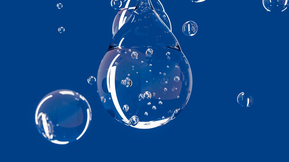 Close-up of water drop with bubbles in blue liquid background