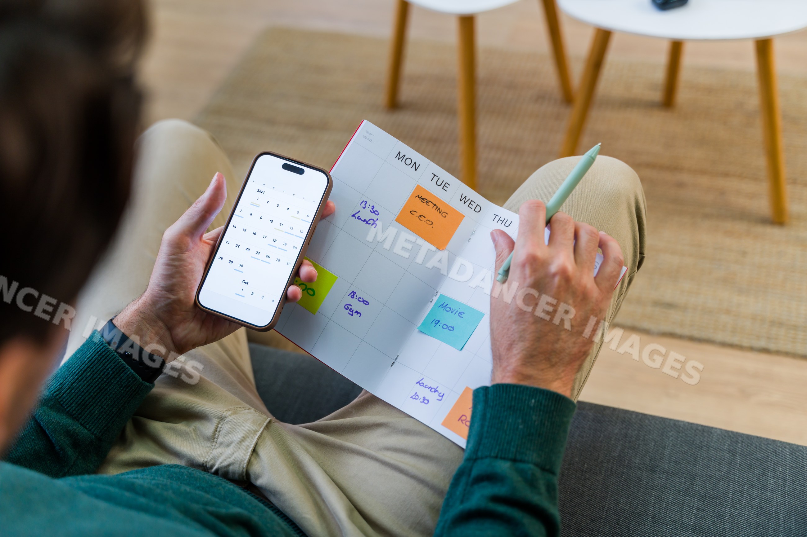 Male planning a monthly schedule with calendar planner and smartphone