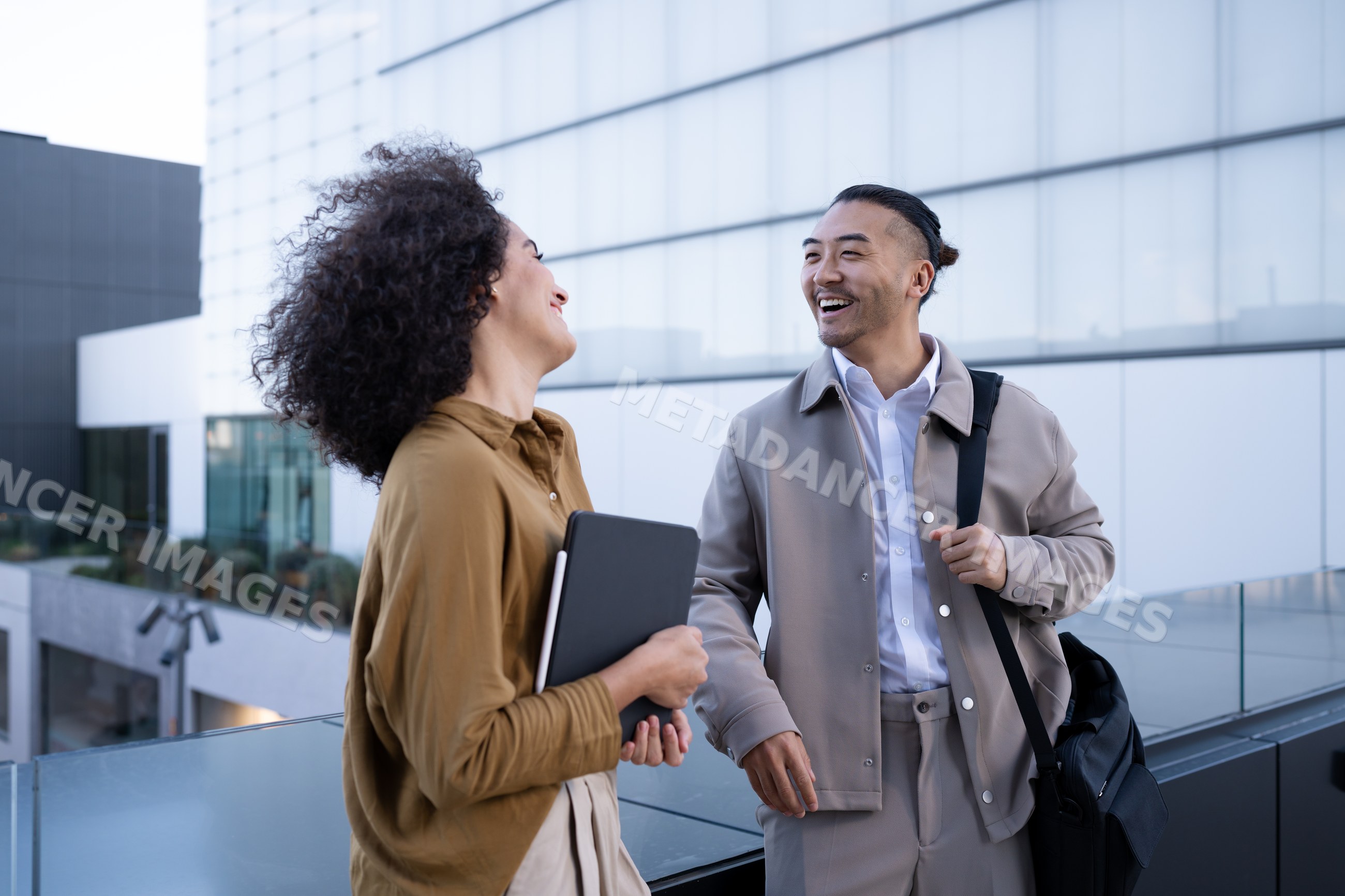 Two colleagues sharing a light moment on an outdoor terrace