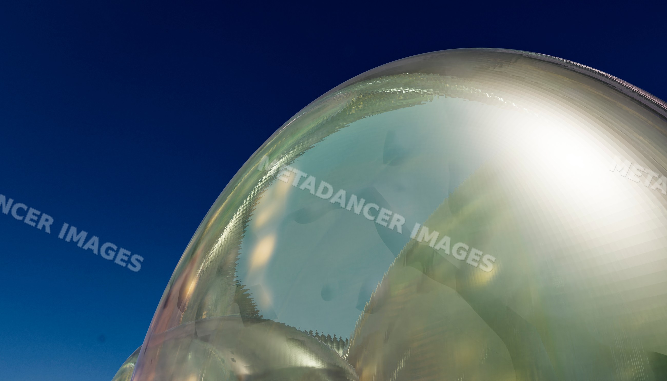 Glass sculpture reflecting distorted figure on curved shiny surface