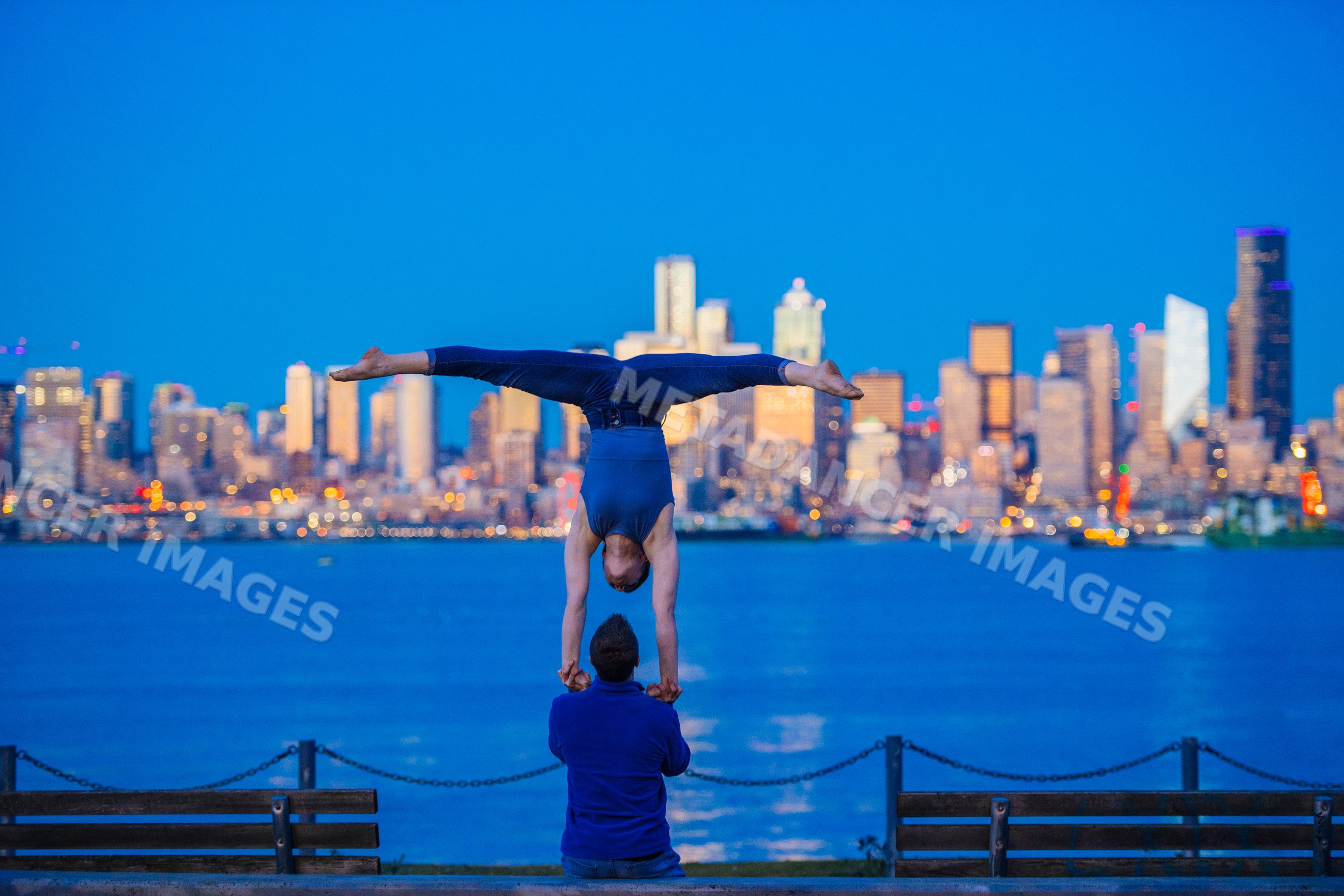 Partner acrobatics handstand balance with Seattle skyline waterfront