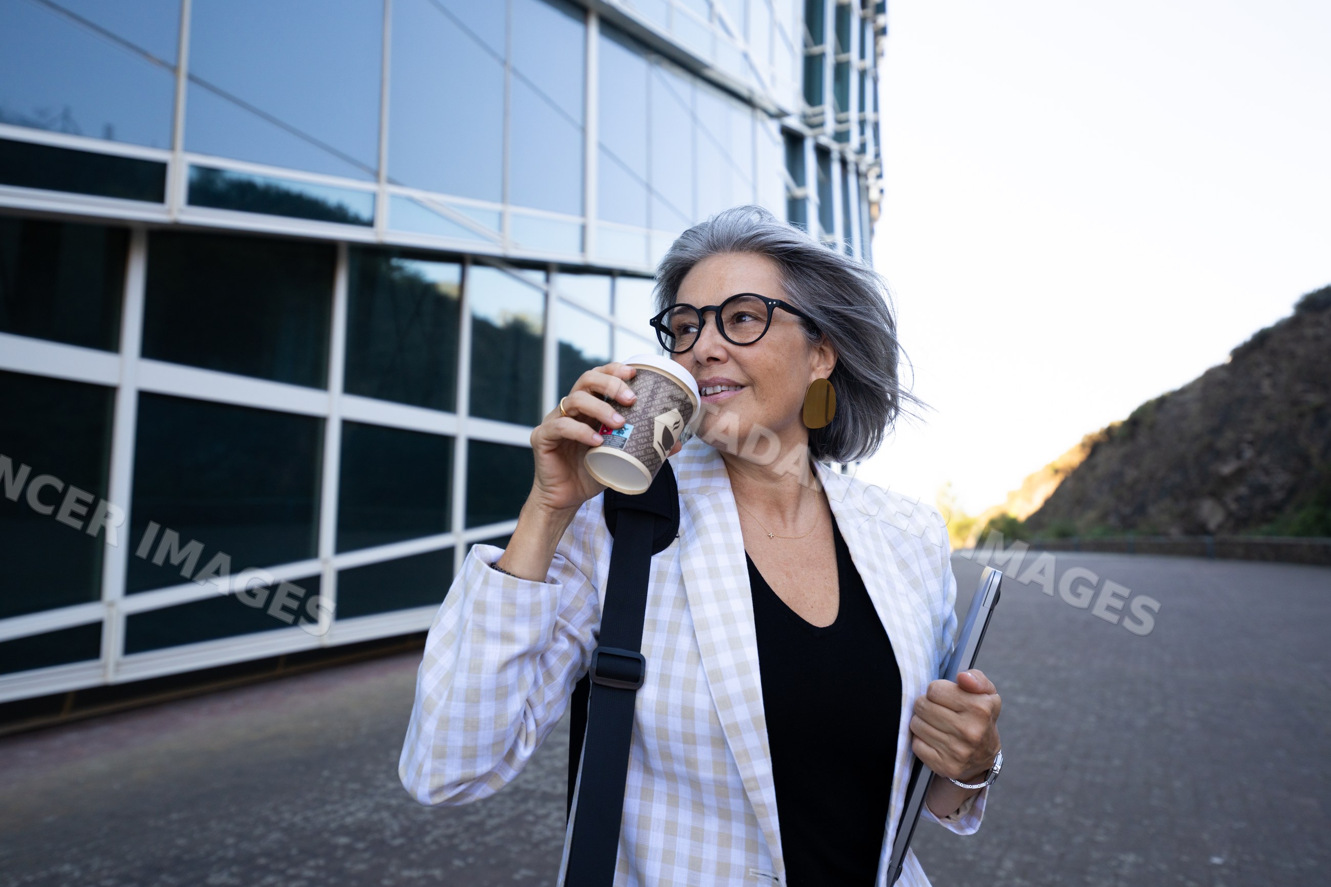 White woman with coffee and tablet near modern building outdoors