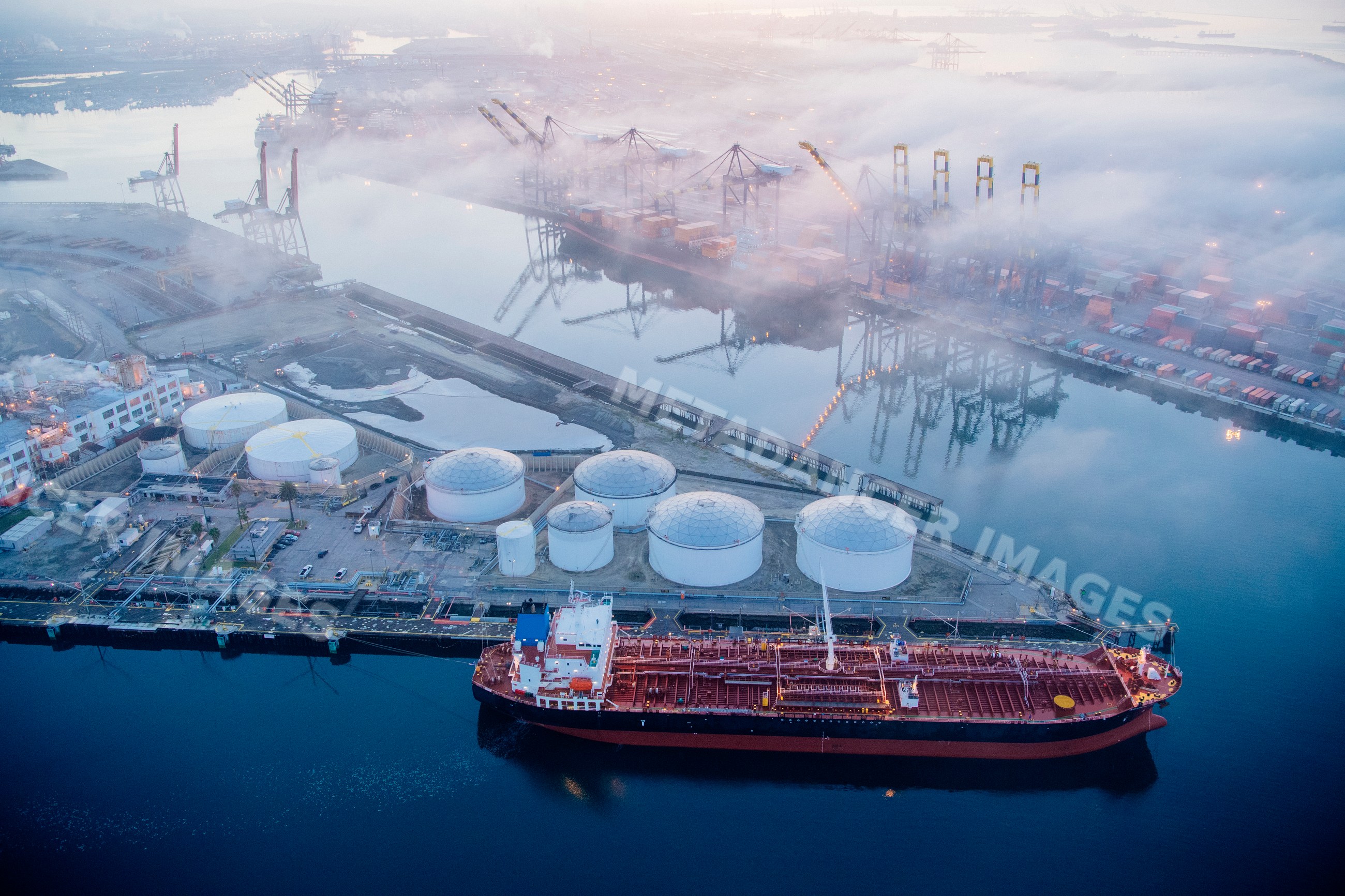 Oil tanker docked near oil storage tanks at a major port