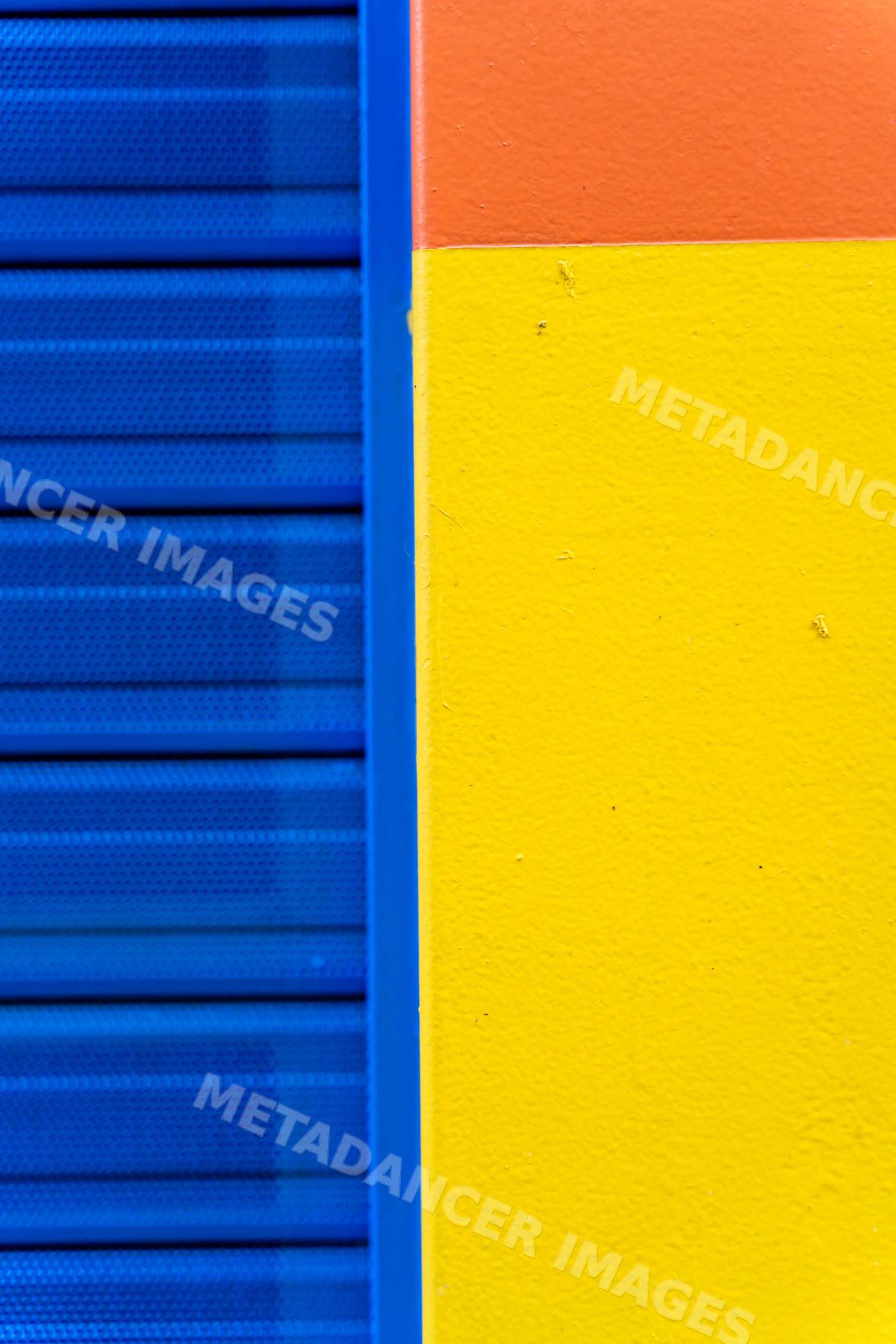 Colorful textured wall corner with blue, yellow, and orange sections