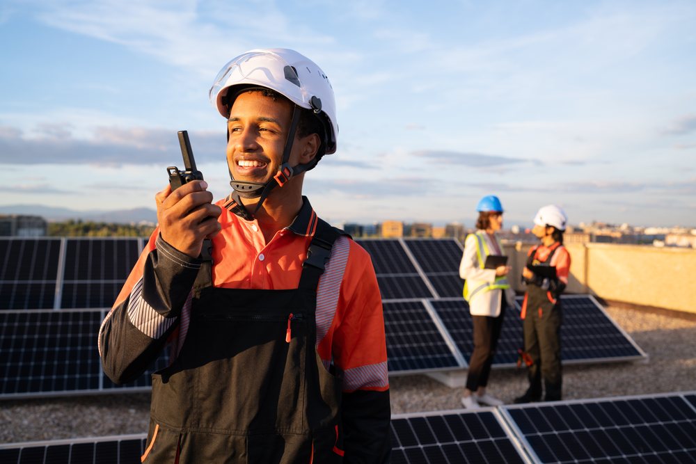 Solar energy technician communicating on rooftop with solar panels
