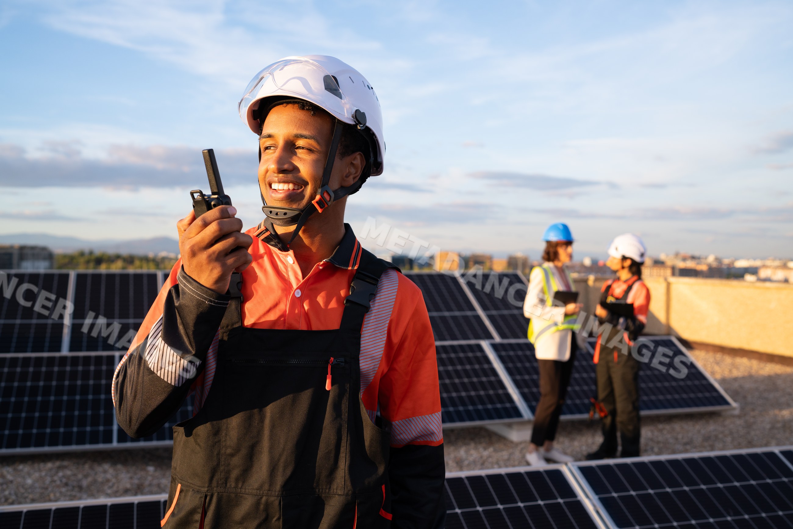 Solar energy technician communicating on rooftop with solar panels