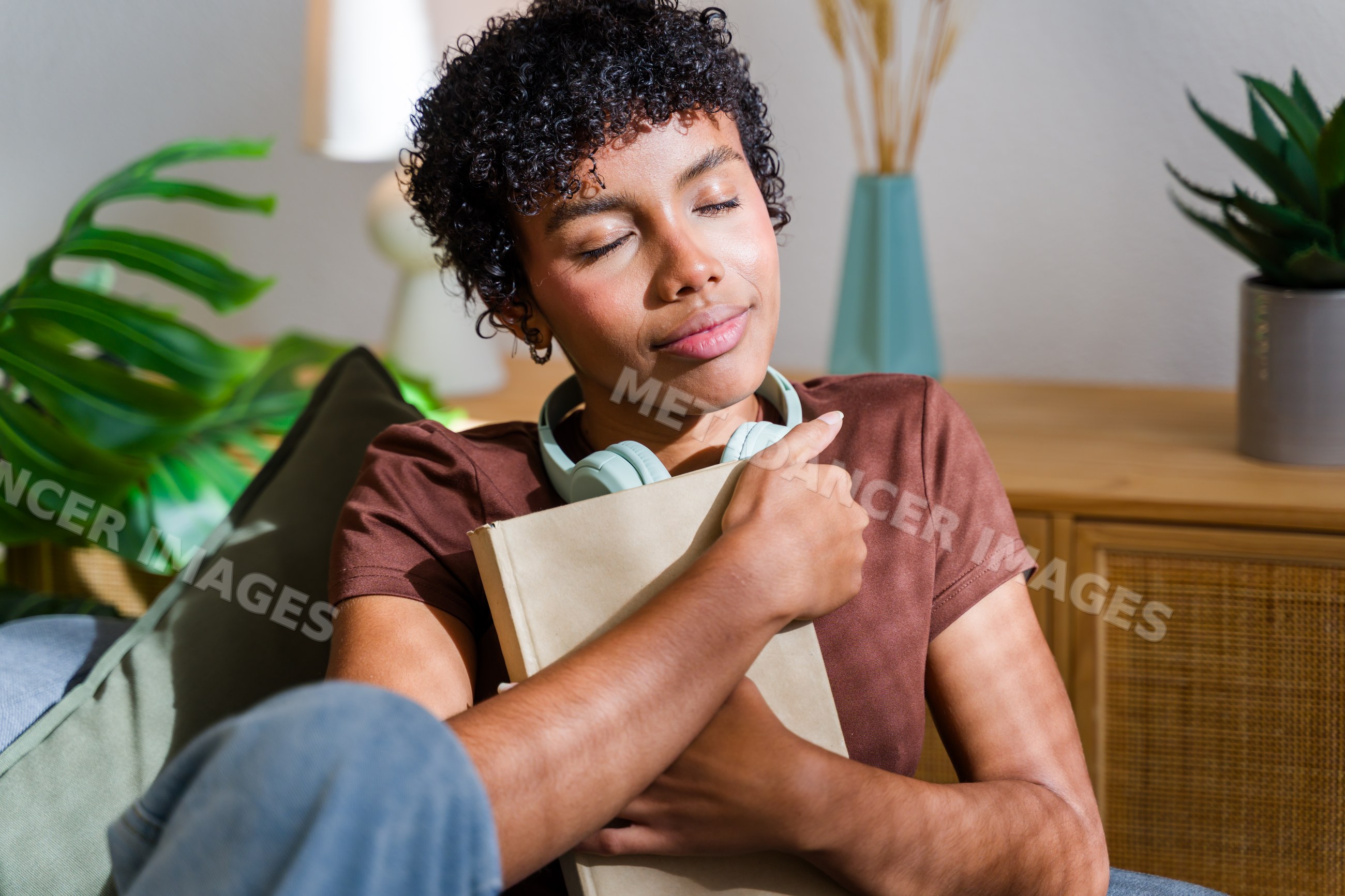 African American woman hugging book with closed eyes and headphones