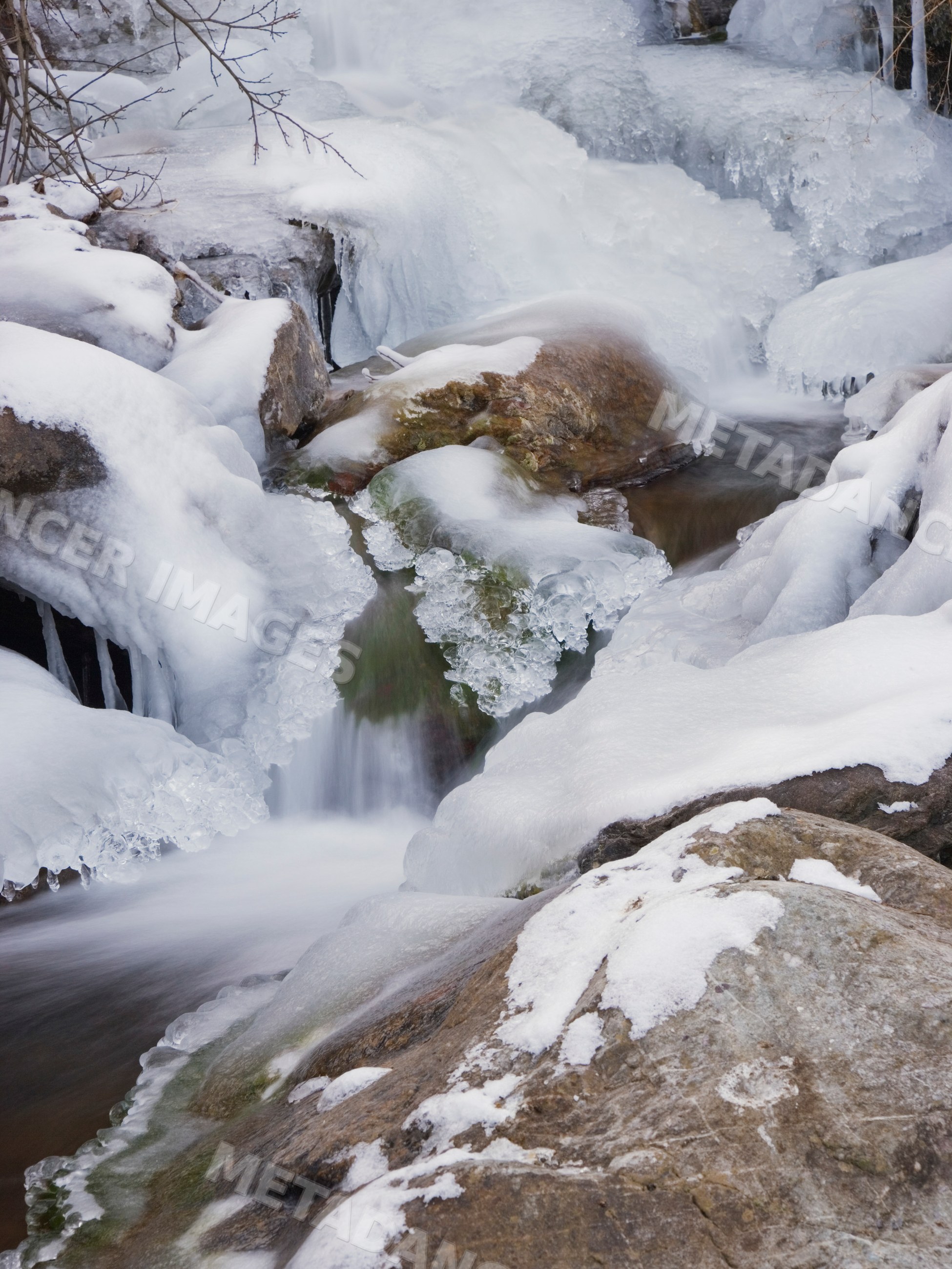 Winter frozen stream flowing over snow-covered rocks