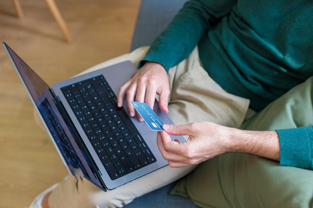 White man holding credit card at home