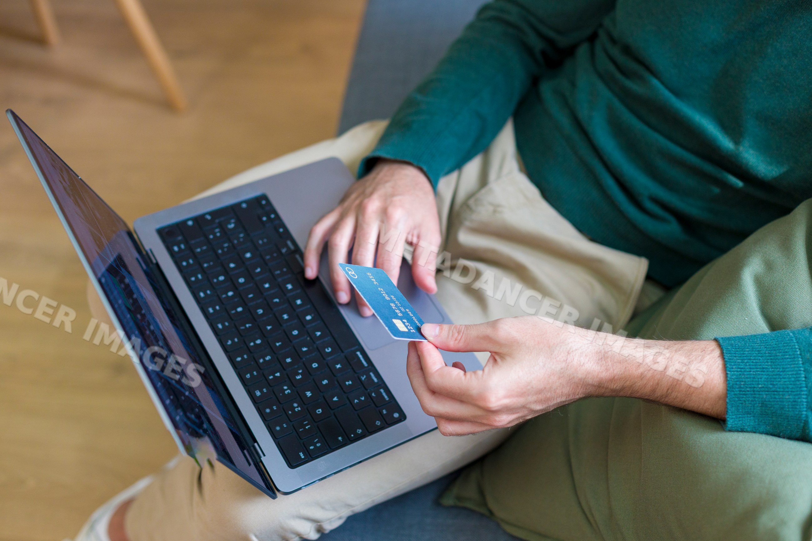 White man holding credit card at home