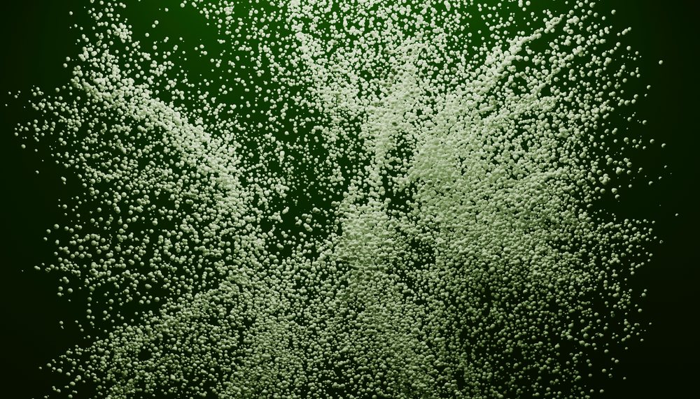 Cluster of white foam bubbles dispersing over dark green background