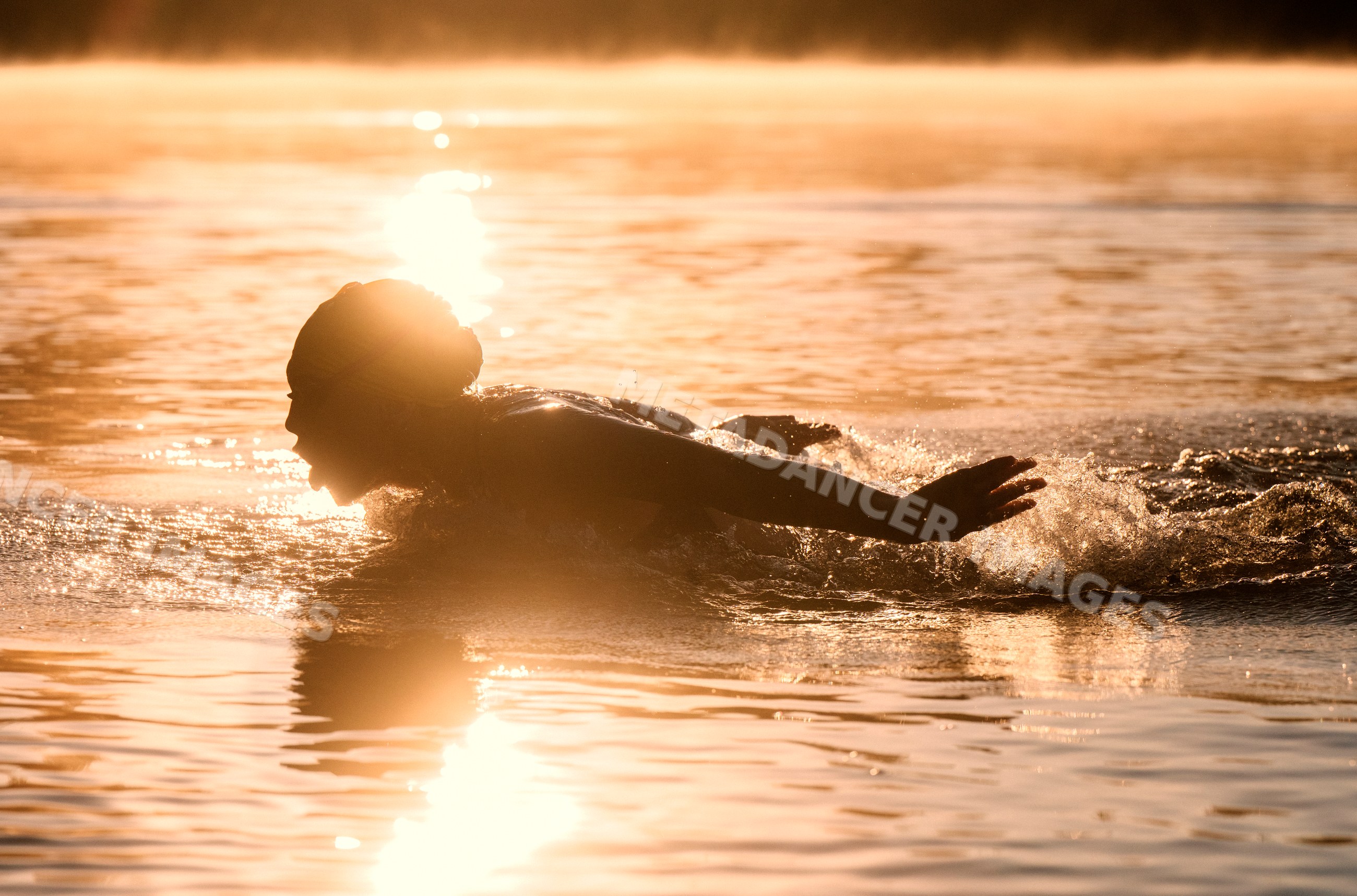 White person practicing open water swimming at sunrise in USA