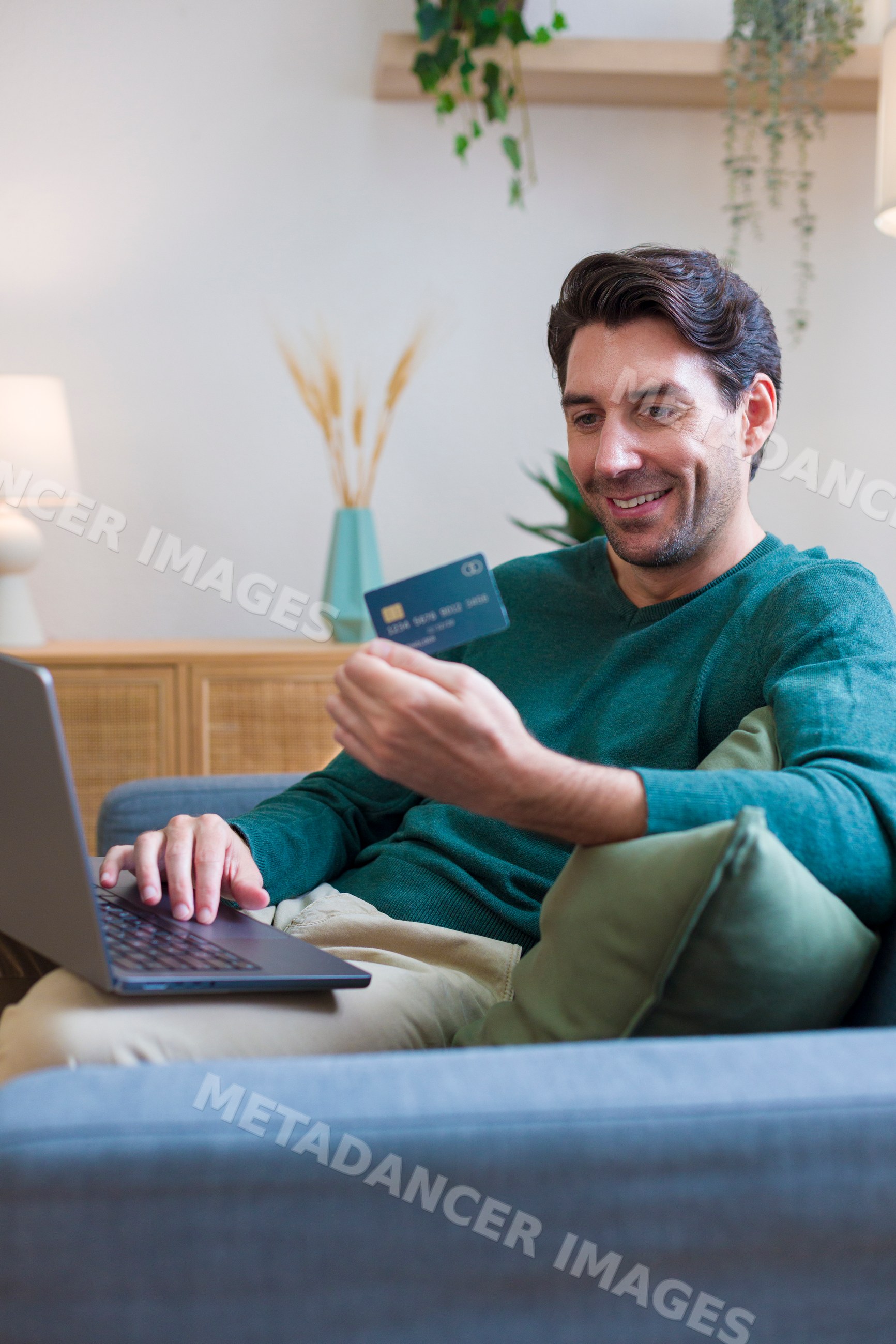 White man using laptop and credit card at home