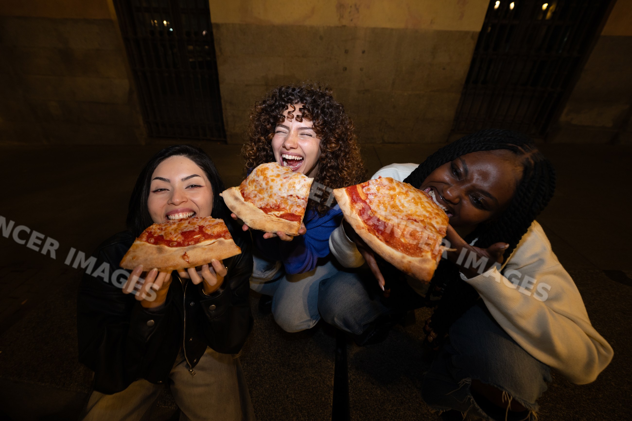 Three Hispanic, white and Black women enjoying cheese pizza slices