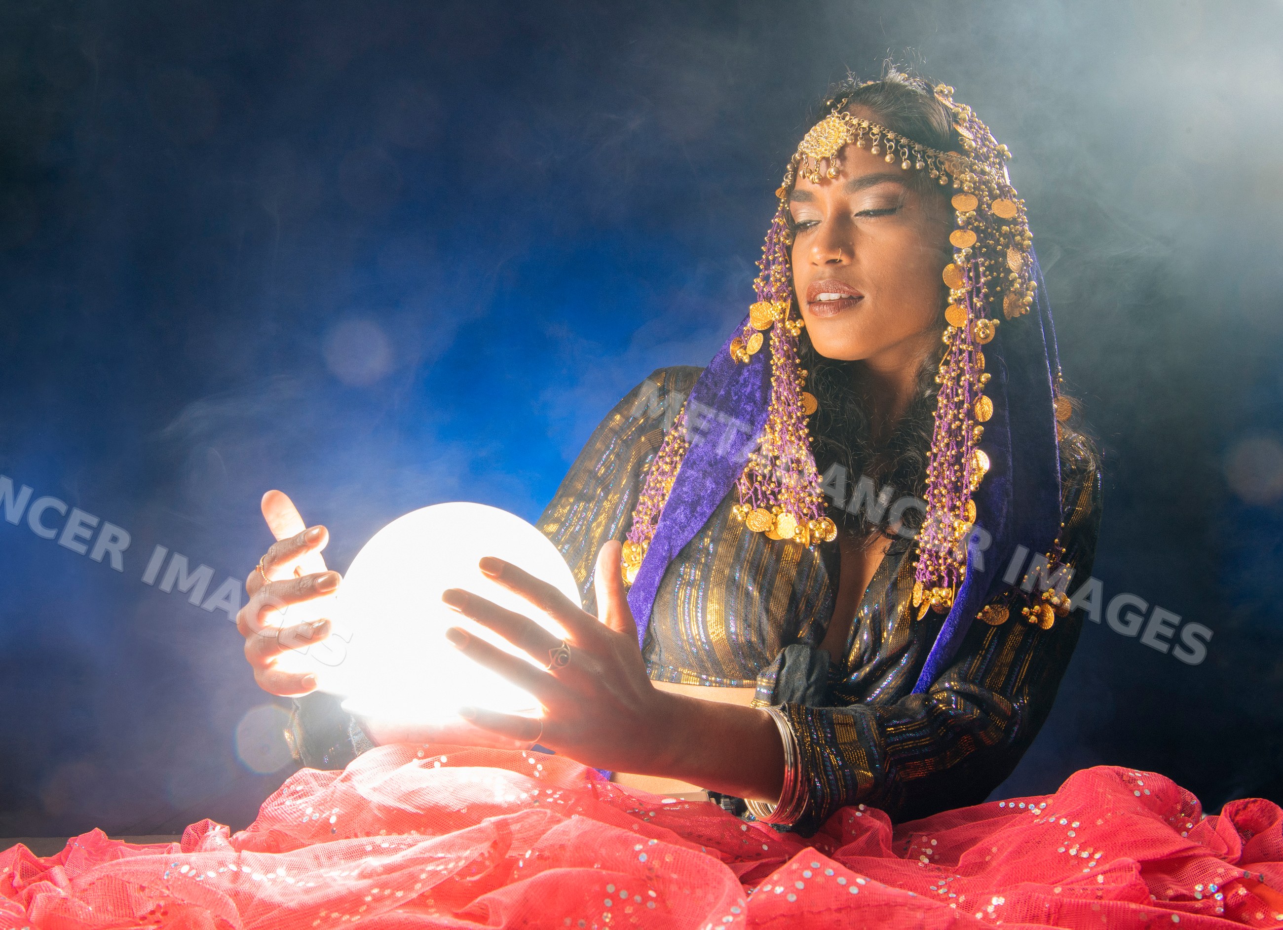 A fortune teller South Asian woman holds a glowing crystal ball