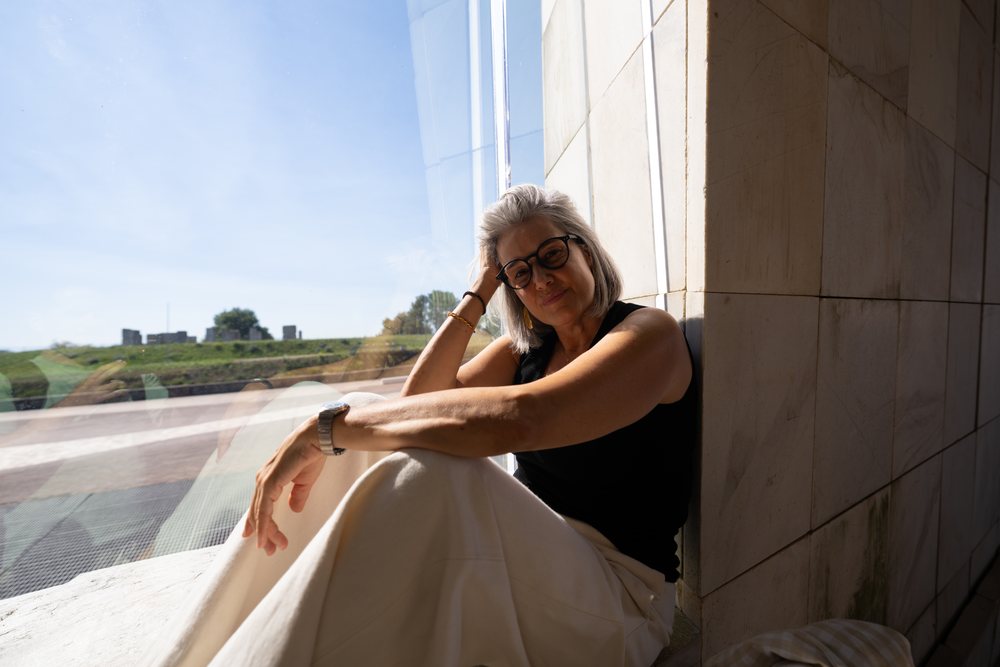 White woman sitting by window inside modern building with urban view