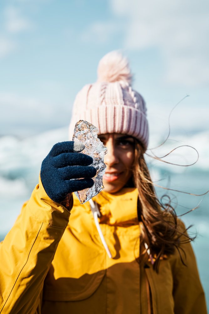 A white woman holding a piece of ice outdoors