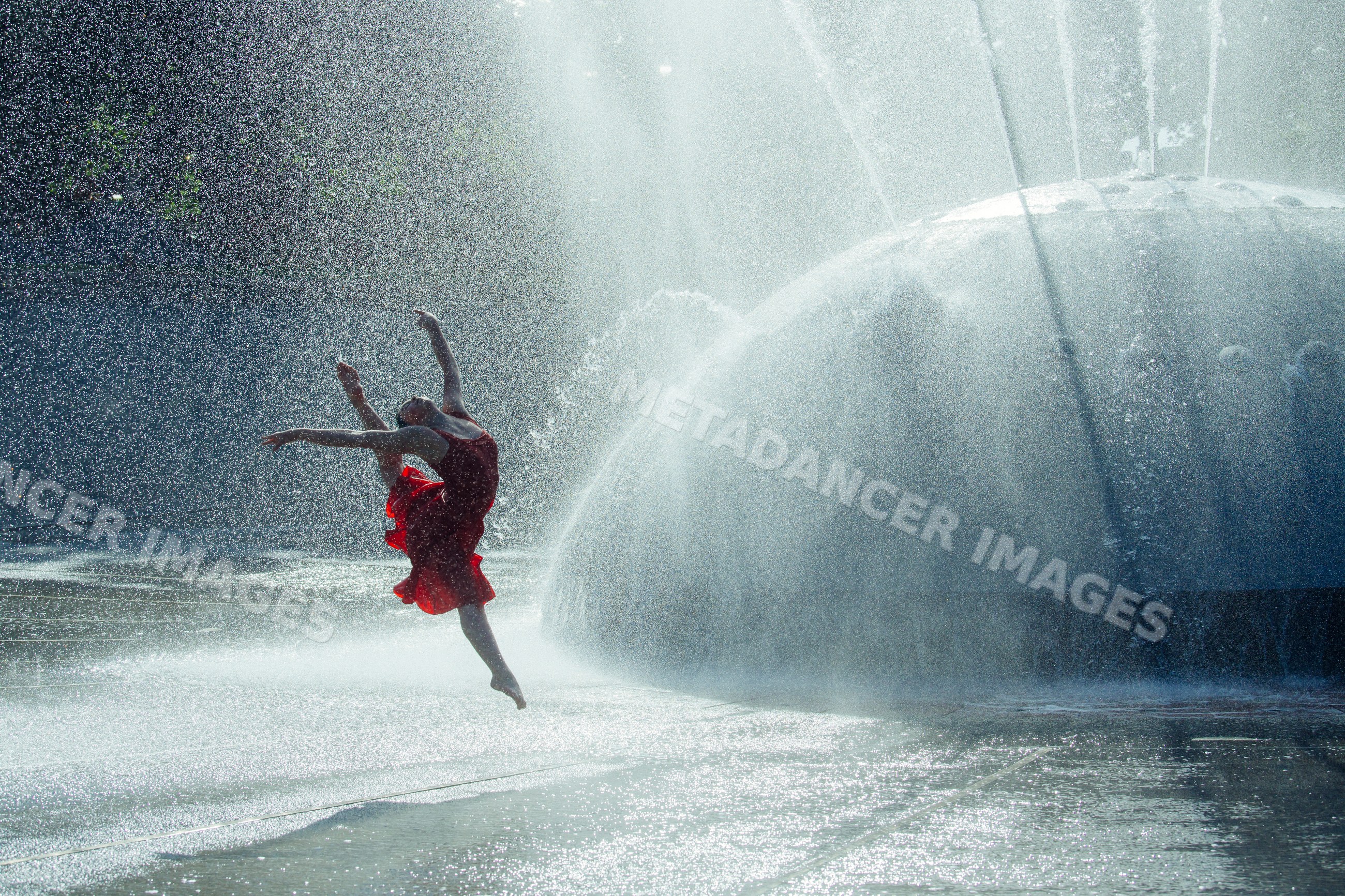 White dancer leaping through water spray from outdoor fountain