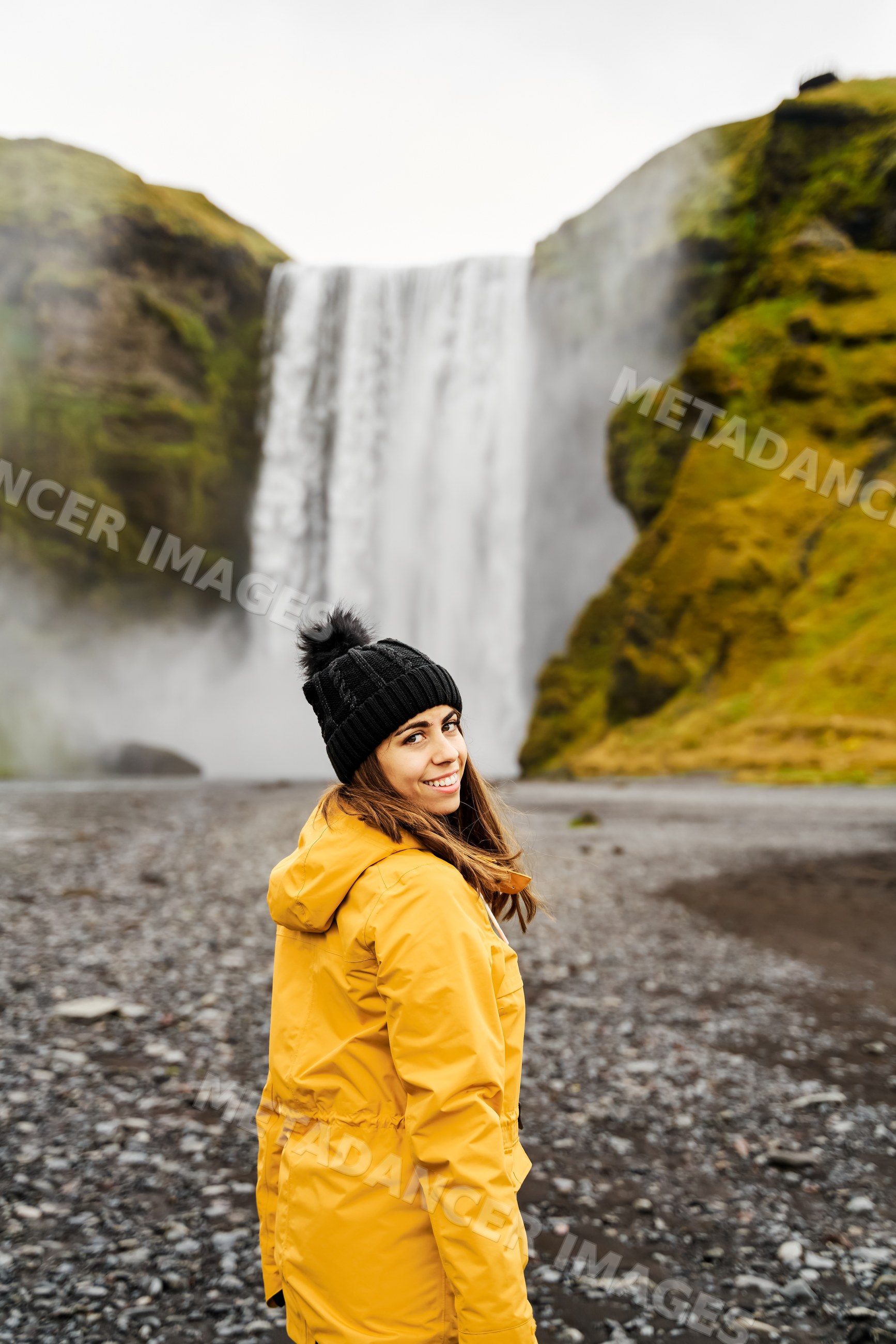 A white woman explores a waterfall on a misty day