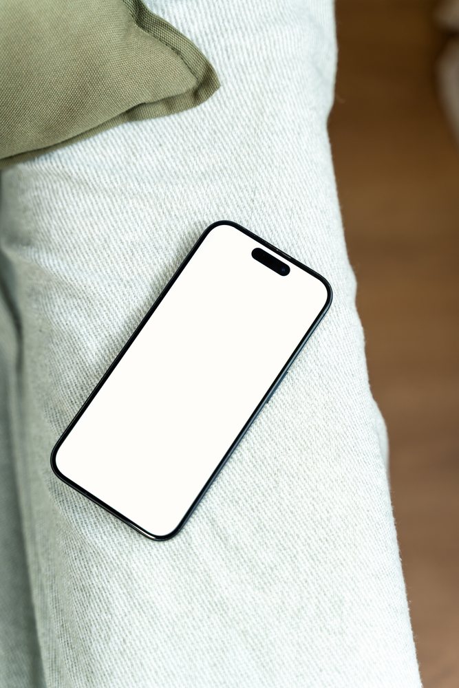 Smartphone with blank white screen resting on textile surface