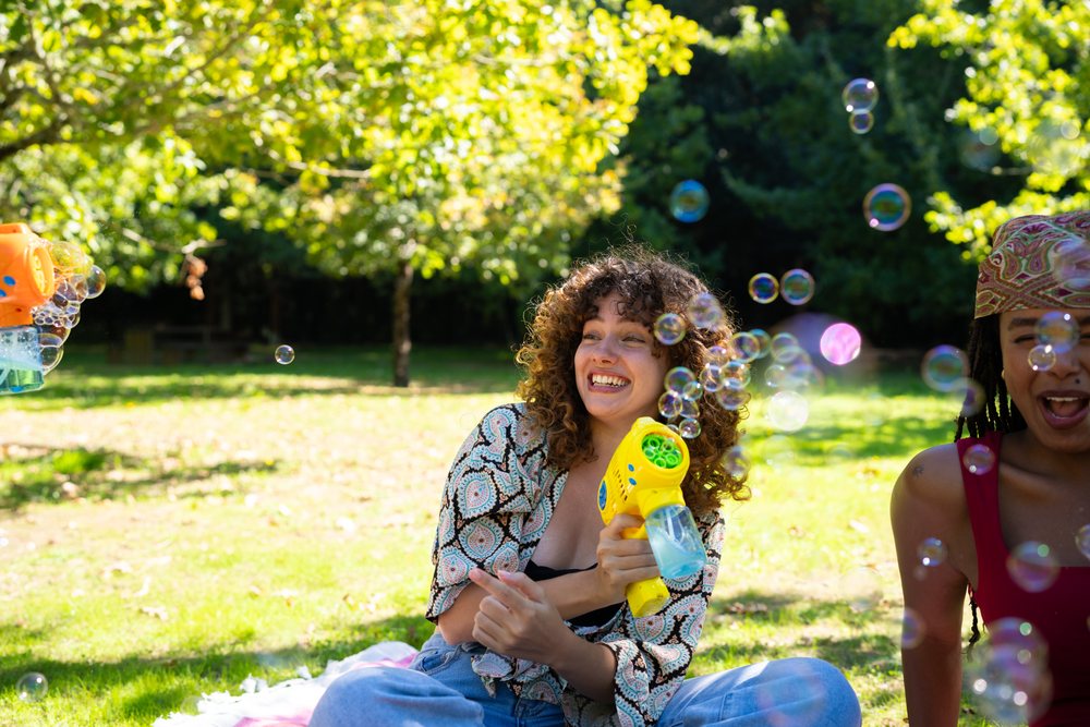 African American and white woman enjoying bubbles with bubble gun
