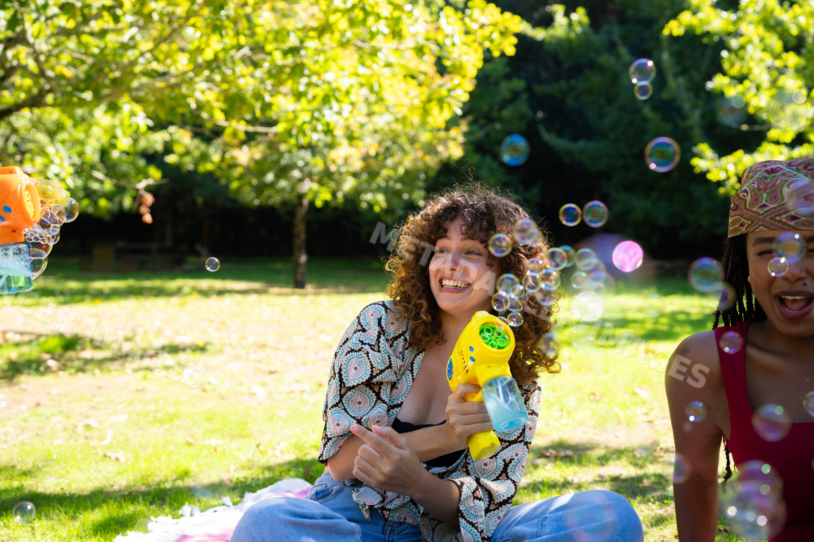African American and white woman enjoying bubbles with bubble gun