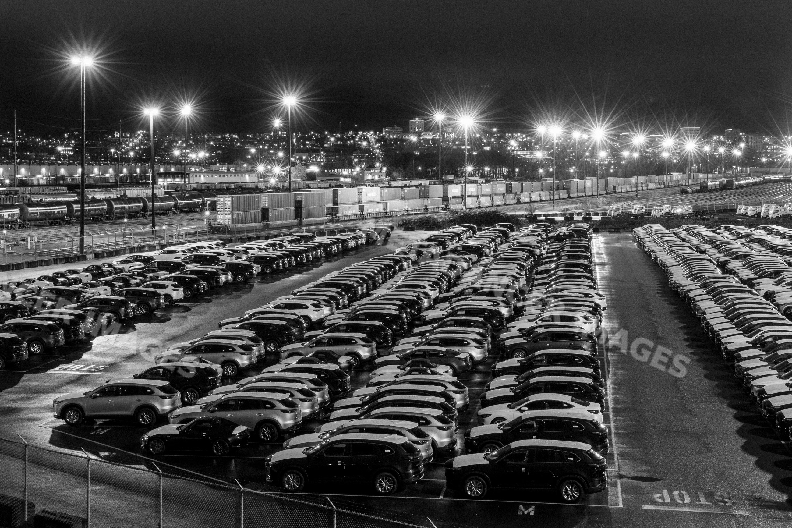 Large parking lot with parked cars and railway cargo containers