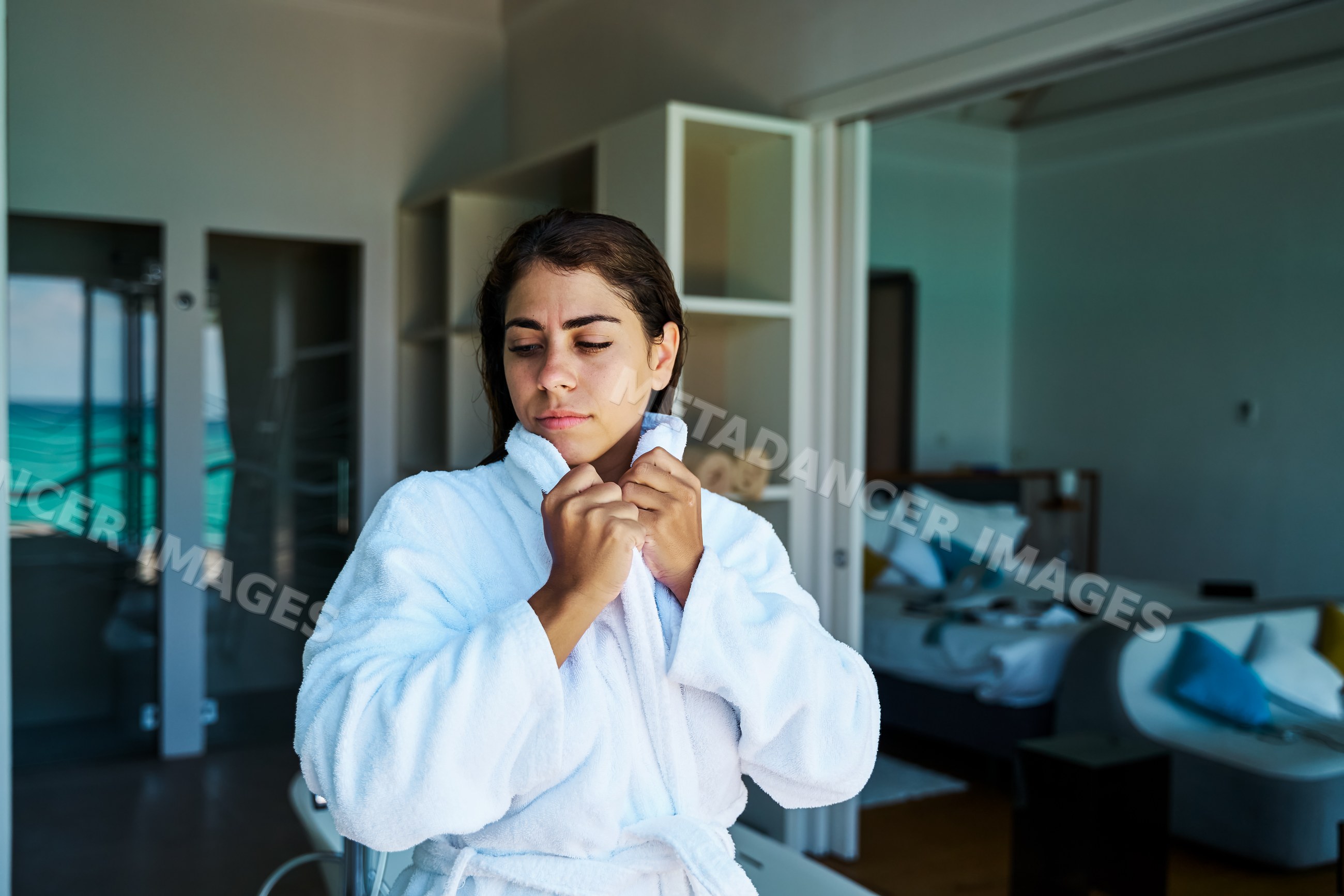A woman wearing a white bathrobe relaxes in a hotel room in a hotel