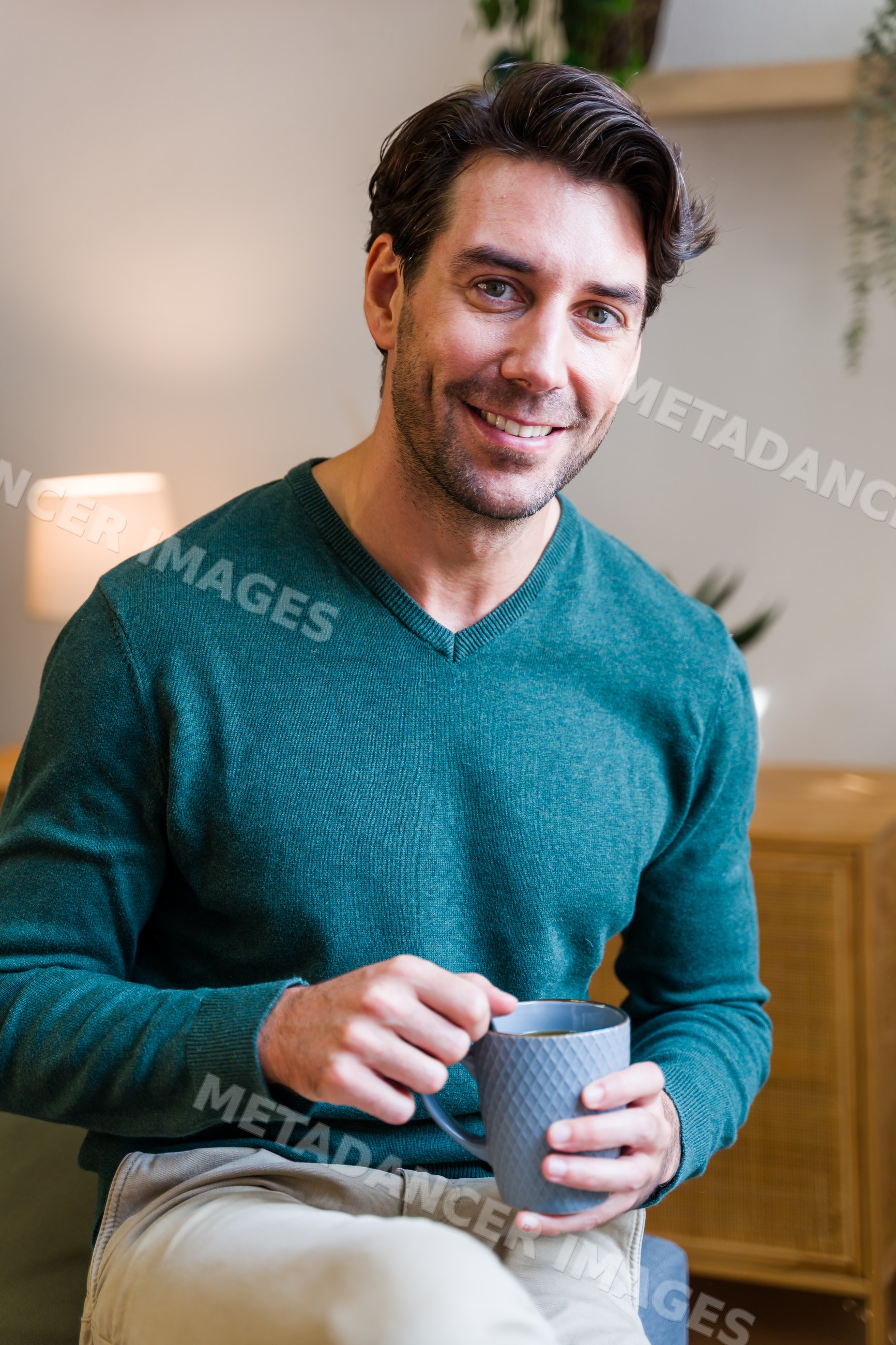 White man enjoying coffee indoors at home in cozy living room