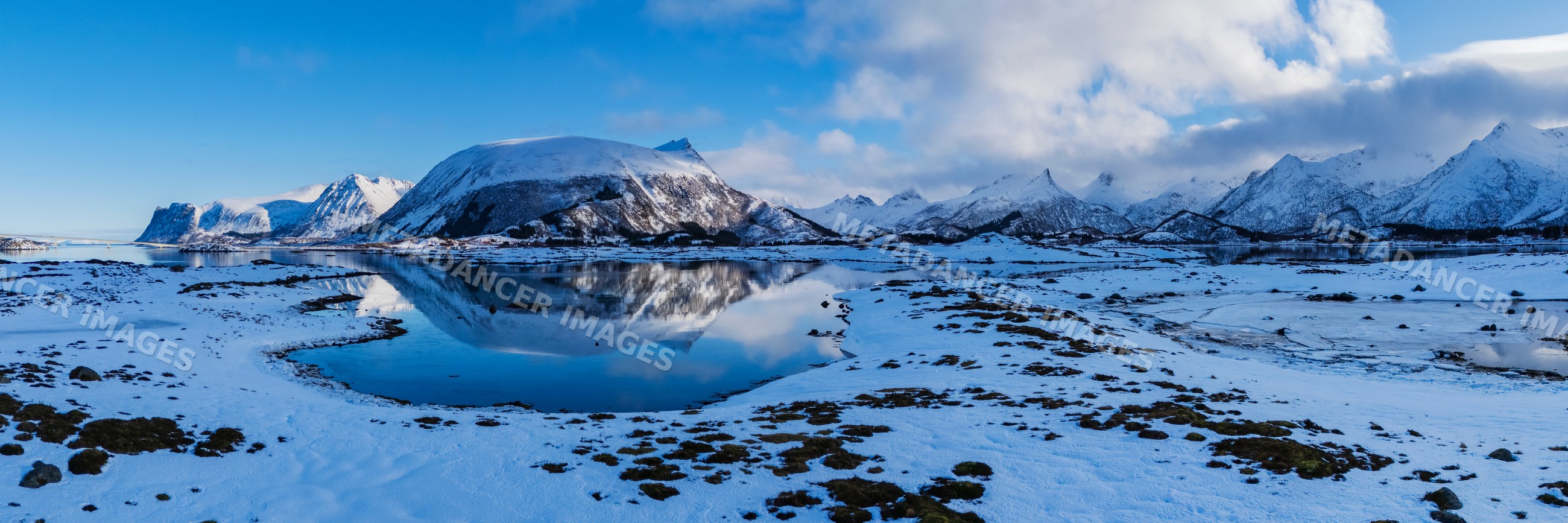 Snow-covered mountains reflecting in Landmeen Fjord in Lofoten Norway